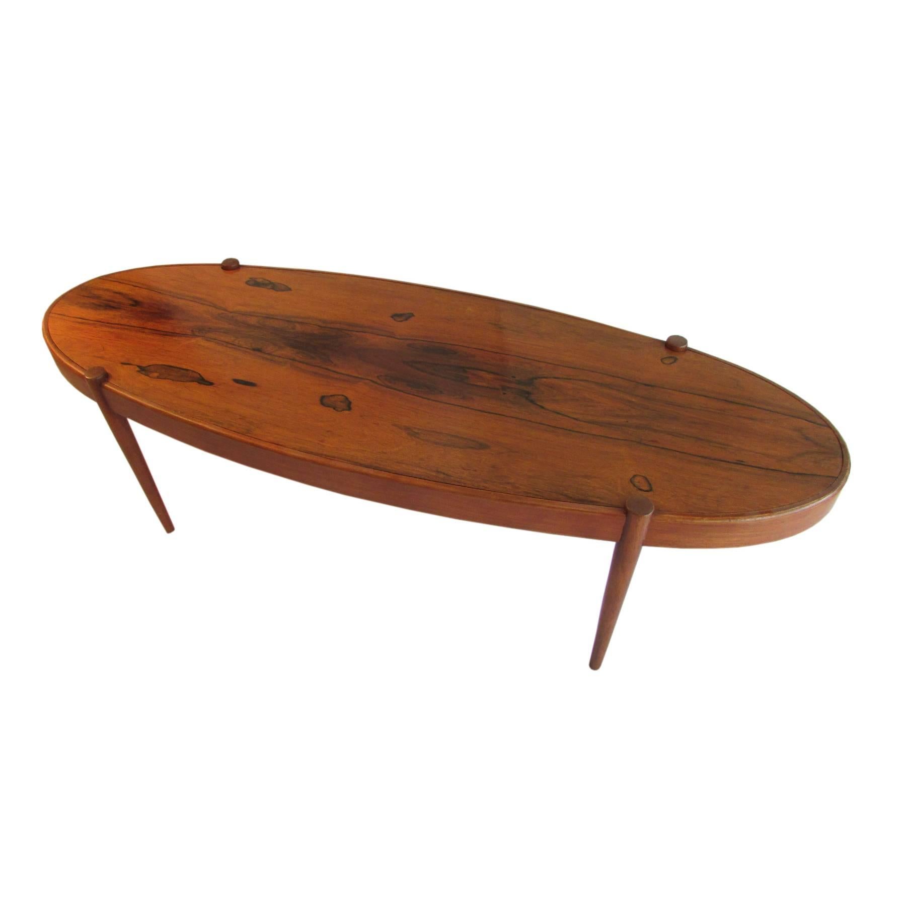 This elliptic rosewood coffee table show a splendid wood pattern topping an interresting structure. The feet seems to cross the girth, giving a floating fullness feeling.
It is a smooth and rare piece of art that will find its place in nearly all