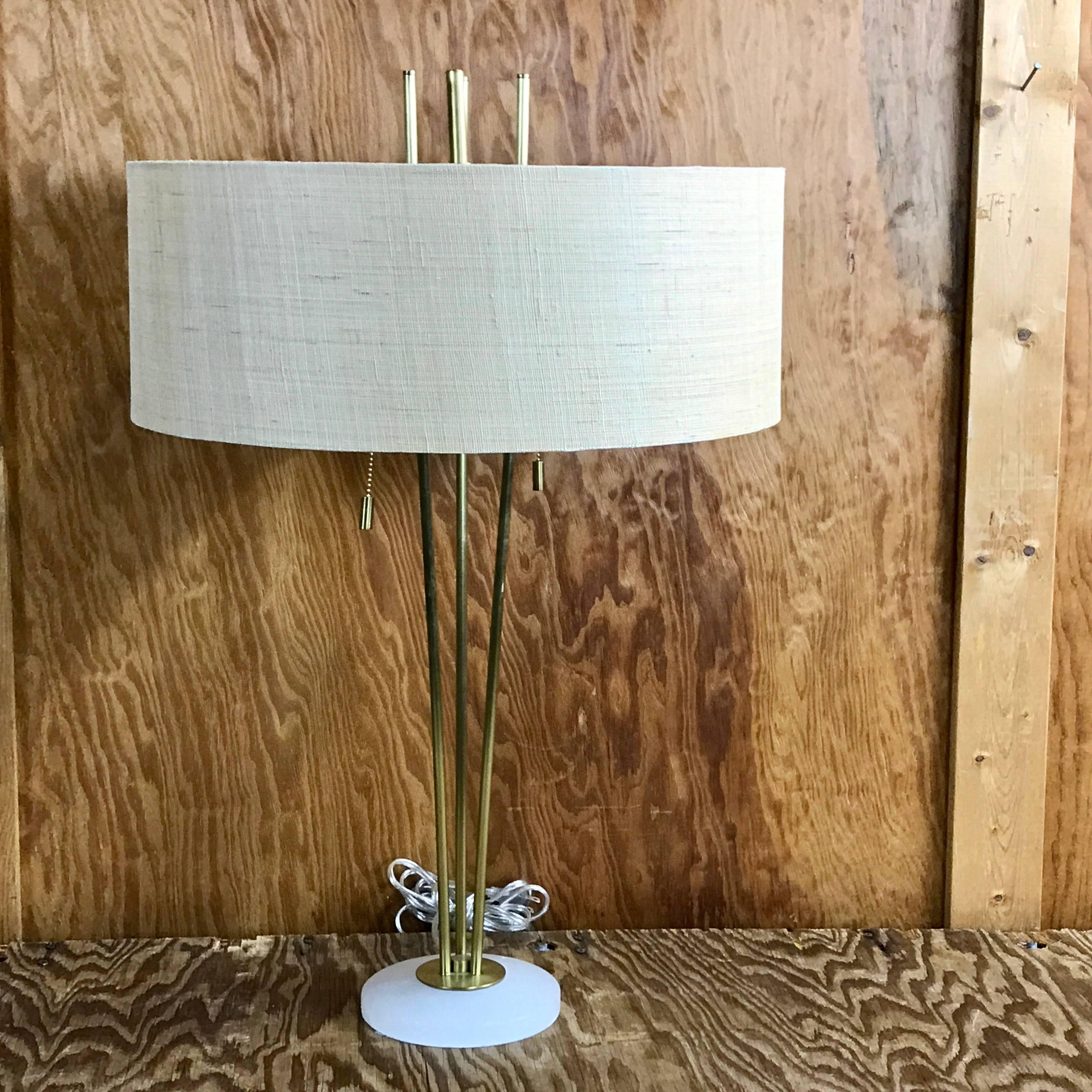 Single brass tripod lamps in the style of Robsjohn-Gibbings raised on 6-inch frosted Lucite bases, complete with custom shades. The shades measure 7.75