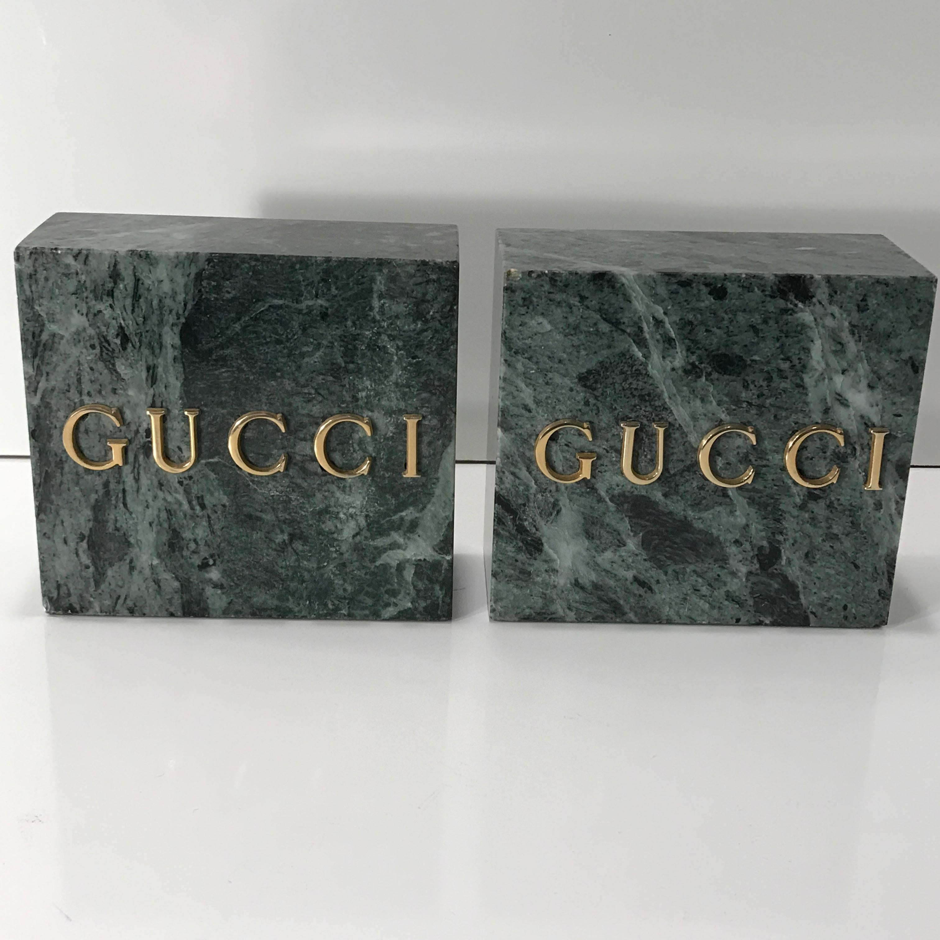 Pair of Gucci Verdigris marble bookends, each one of carved monolith form with inset gilt bronze letters.
