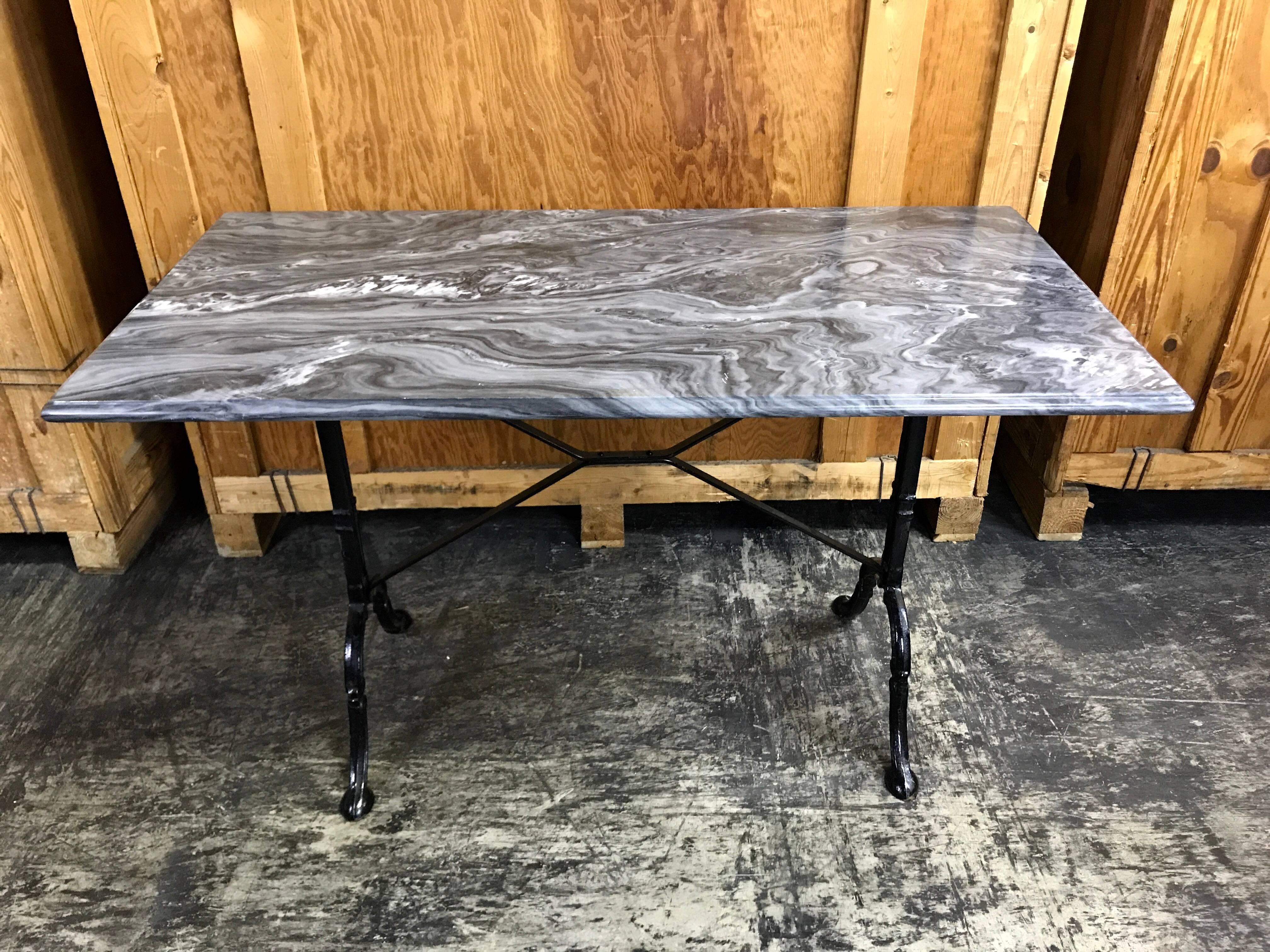 Antique French marble top bakers/bistro table, of rectangular form with beveled variegated marble with deep hues of grey, white and black. Raised on a black iron trestle base. The width of the legs is 19 inches.