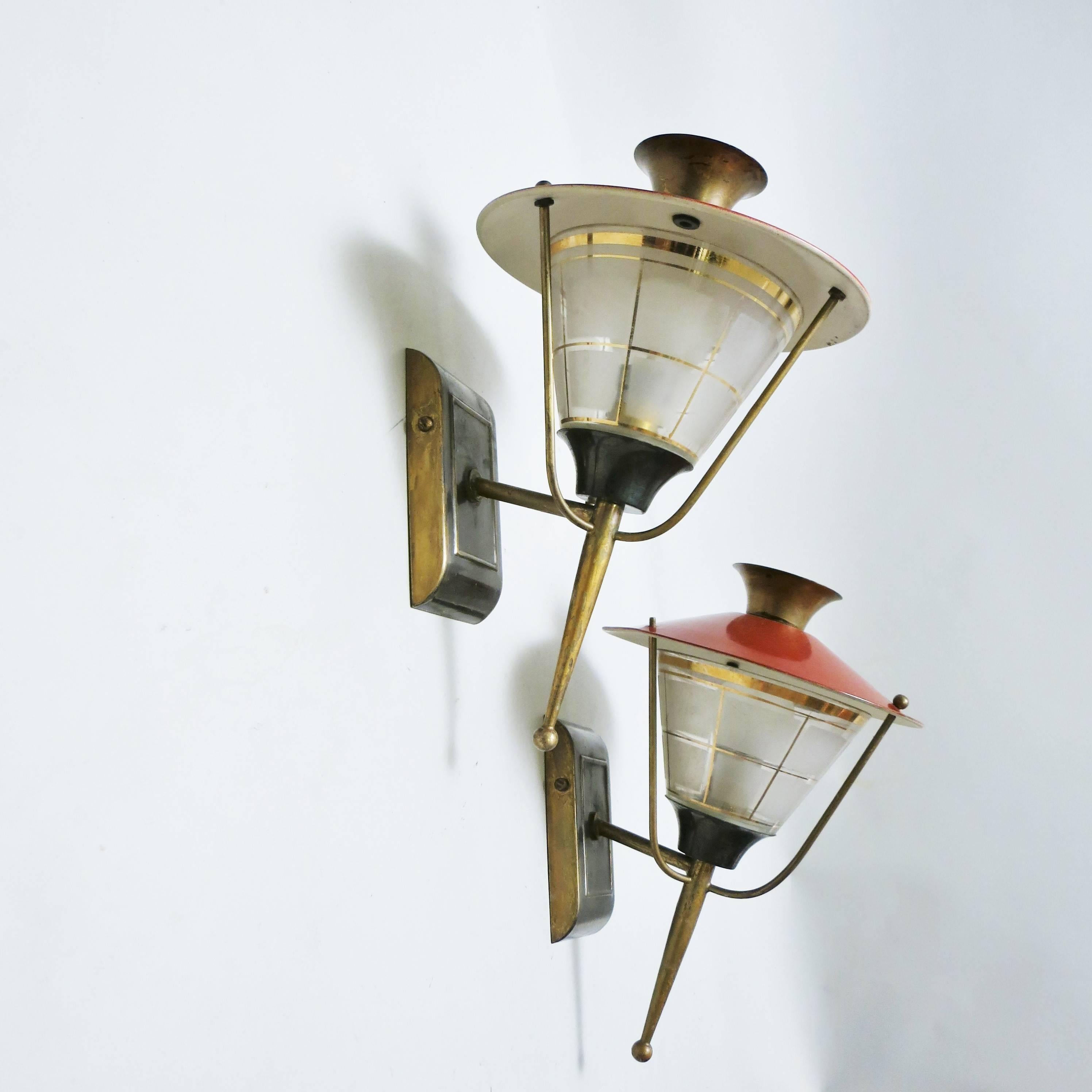 A pair of vintage 1950s French wall-mounted lantern-form fixtures in brass, metal lacquered red, glass attributed to Lunel.