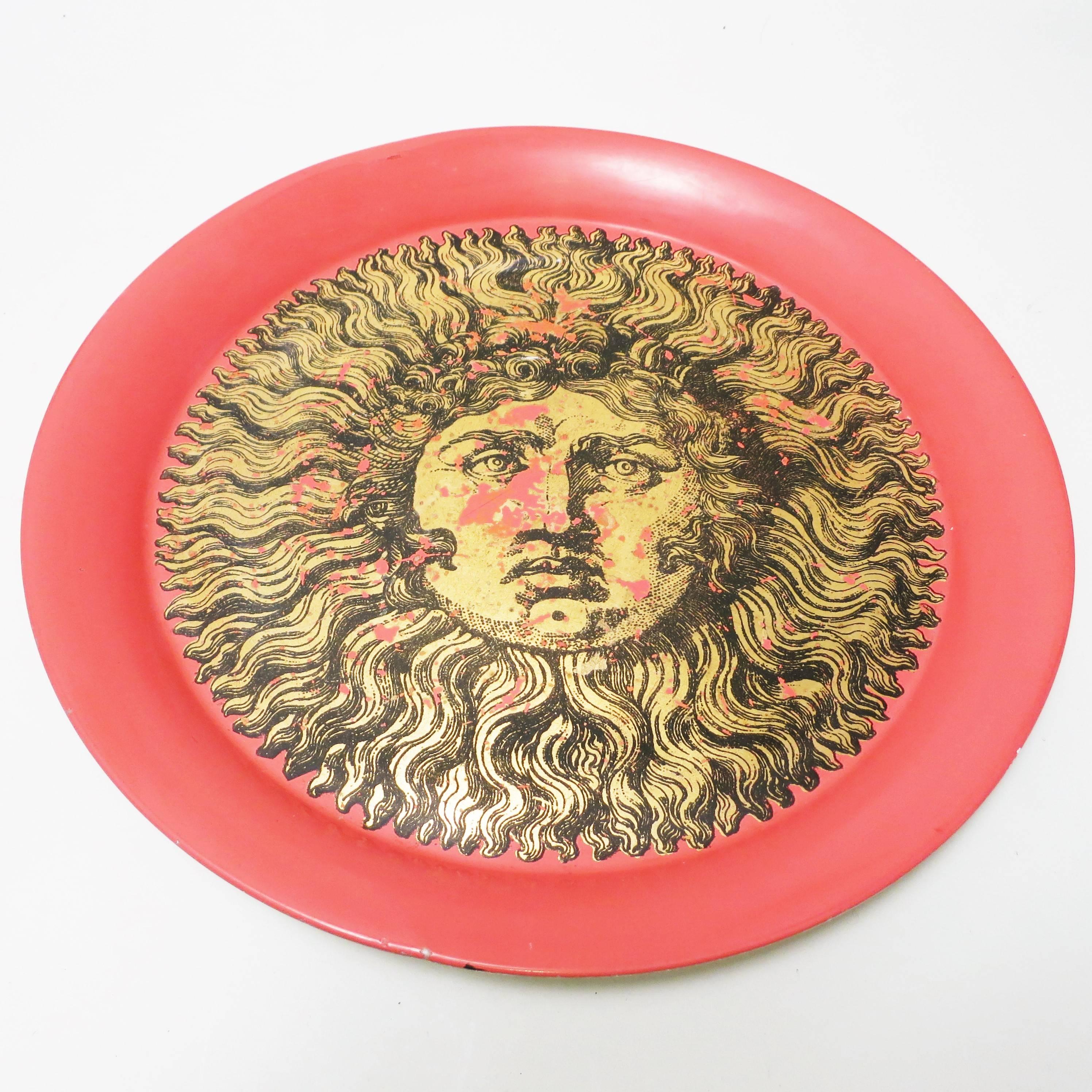 Metal tray with King Sun ‘Sole Ricciuto’ golden and black decoration on a red background
Designed by Piero Fornasetti, and produced by Fornasetti Milano, circa 1950-1960
Labeled by maker on the back side
Some lack of golden decor makes a