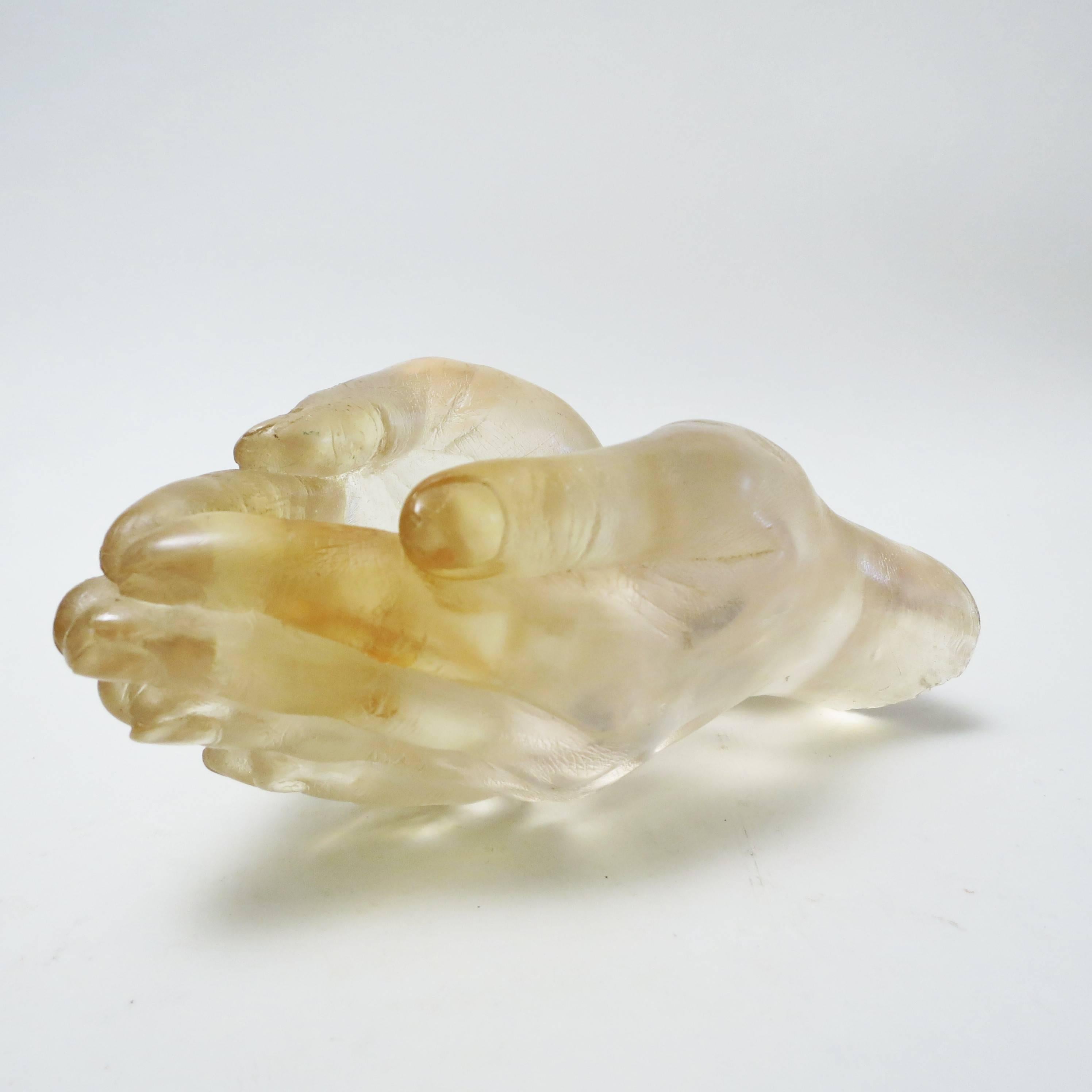 A two hands shaped sculpture in pale yellow colored resin attributed to Pierre Giraudon, France, circa 1968.
The sculpture can take several position and can also be used as a bowl or a vide-poche. 
It is a cast of real hands where fingerprints