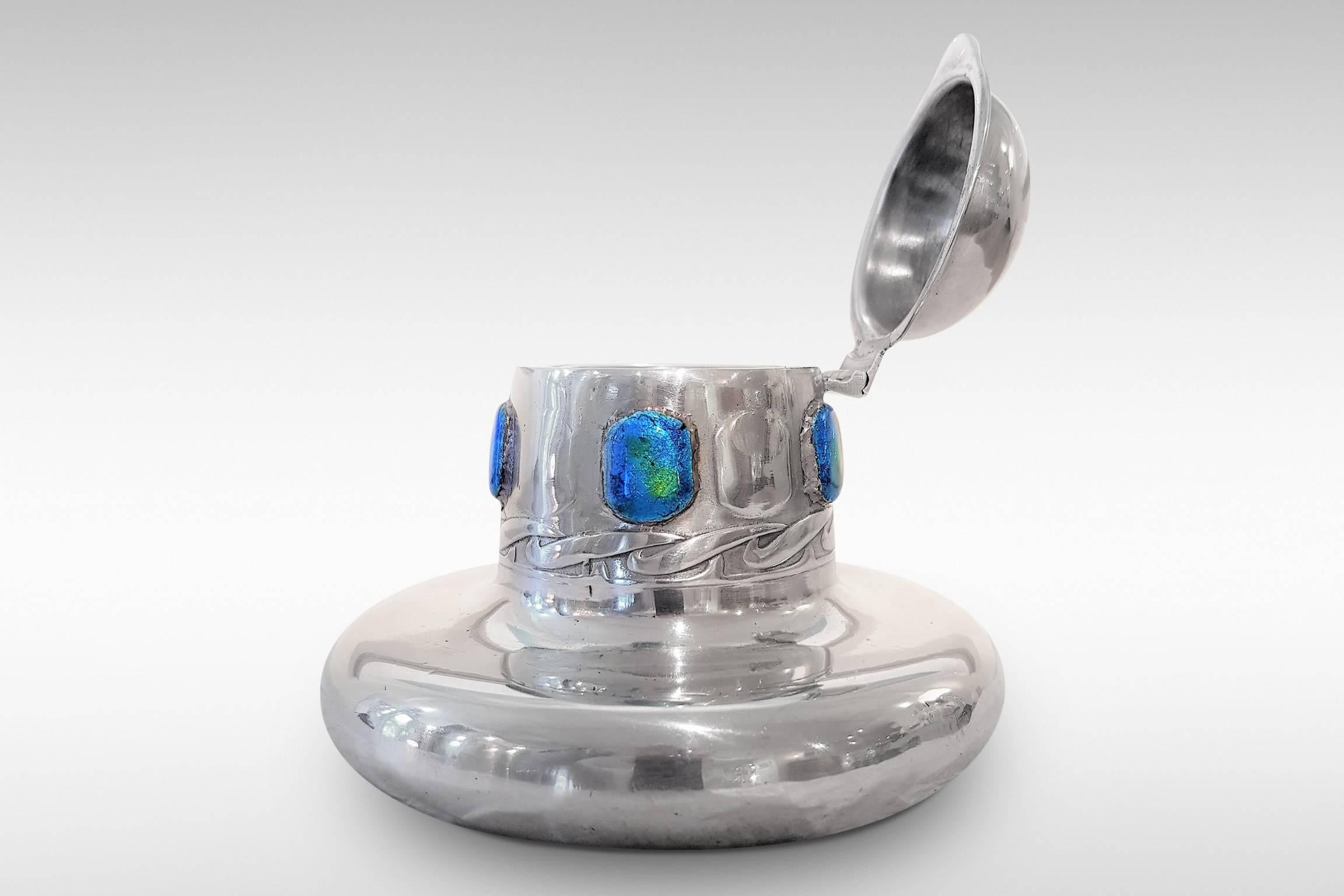 This inkwell in pewter with blue/green enamels was designed Archibald Knox for Liberty and Co's 'Tudric' range of Art Nouveau pewter-ware. It is model 0164 and dates from 1902-1905. Clear glass liner.

Literature: Stephen A Martin, 'Archibald