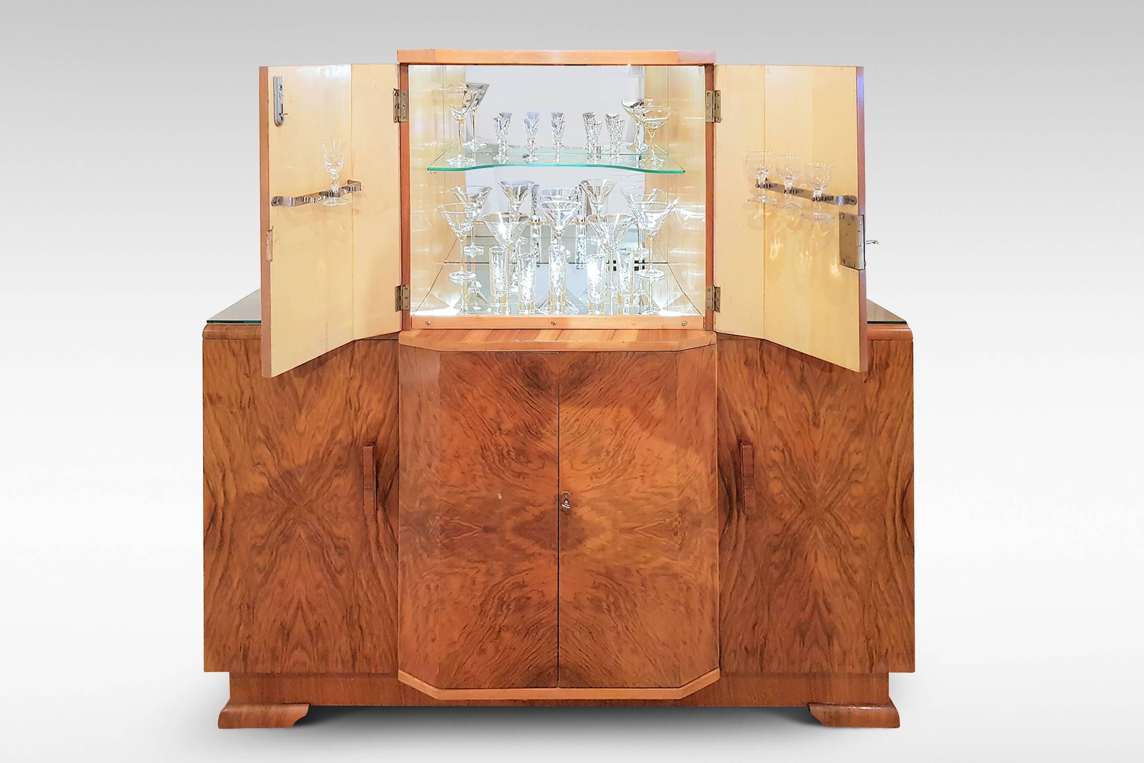 A highly versatile cocktail sideboard in walnut veneers from the Art Deco period, with mirrored and illuminated upper cabinet,
circa 1935-1955.