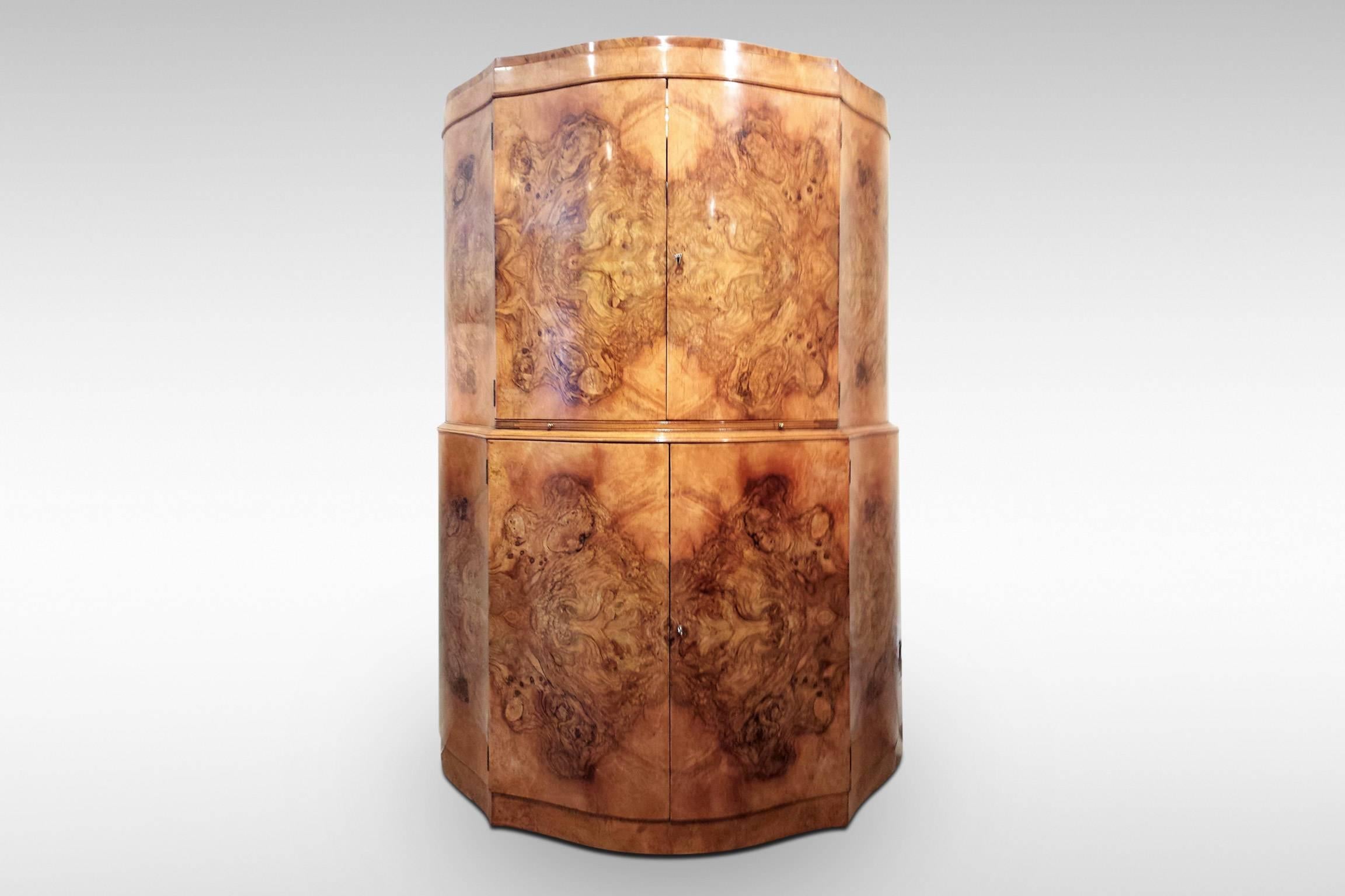 A classic and original Art Deco serpentine design demilune cocktail cabinet in striking figured walnut veneers. Upper doors open to reveal a fitted and mirrored interior. There is a pull-out sliding and mirrored bar surface, and space in the lower