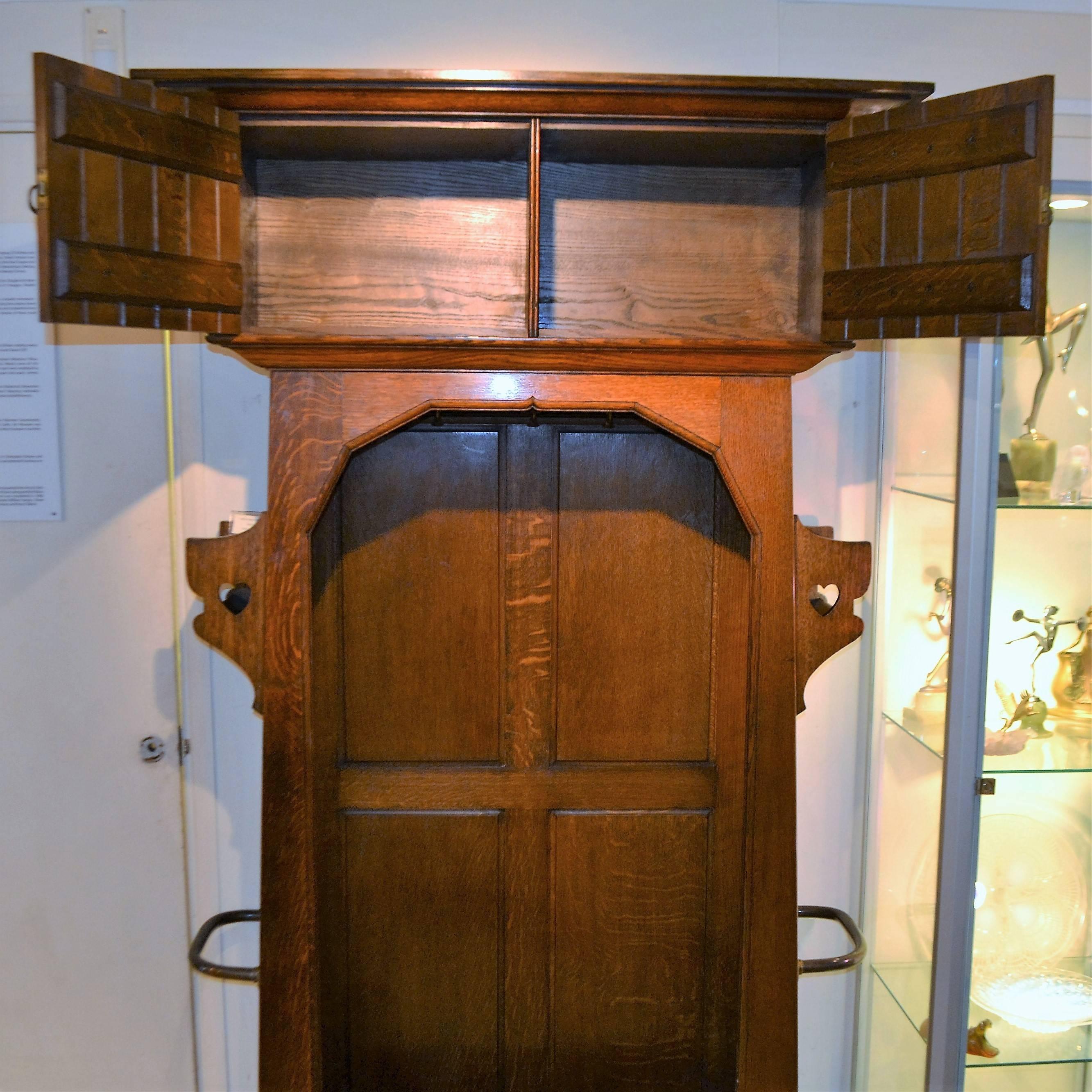 A hall cupboard by leading British manufacturer of Arts & Crafts furniture, Shapland and Petter of Barnstaple. This piece in oak with repousse copper strapwork was designed by their gifted in-house designer William Cowie, circa 1900.

Shapland and