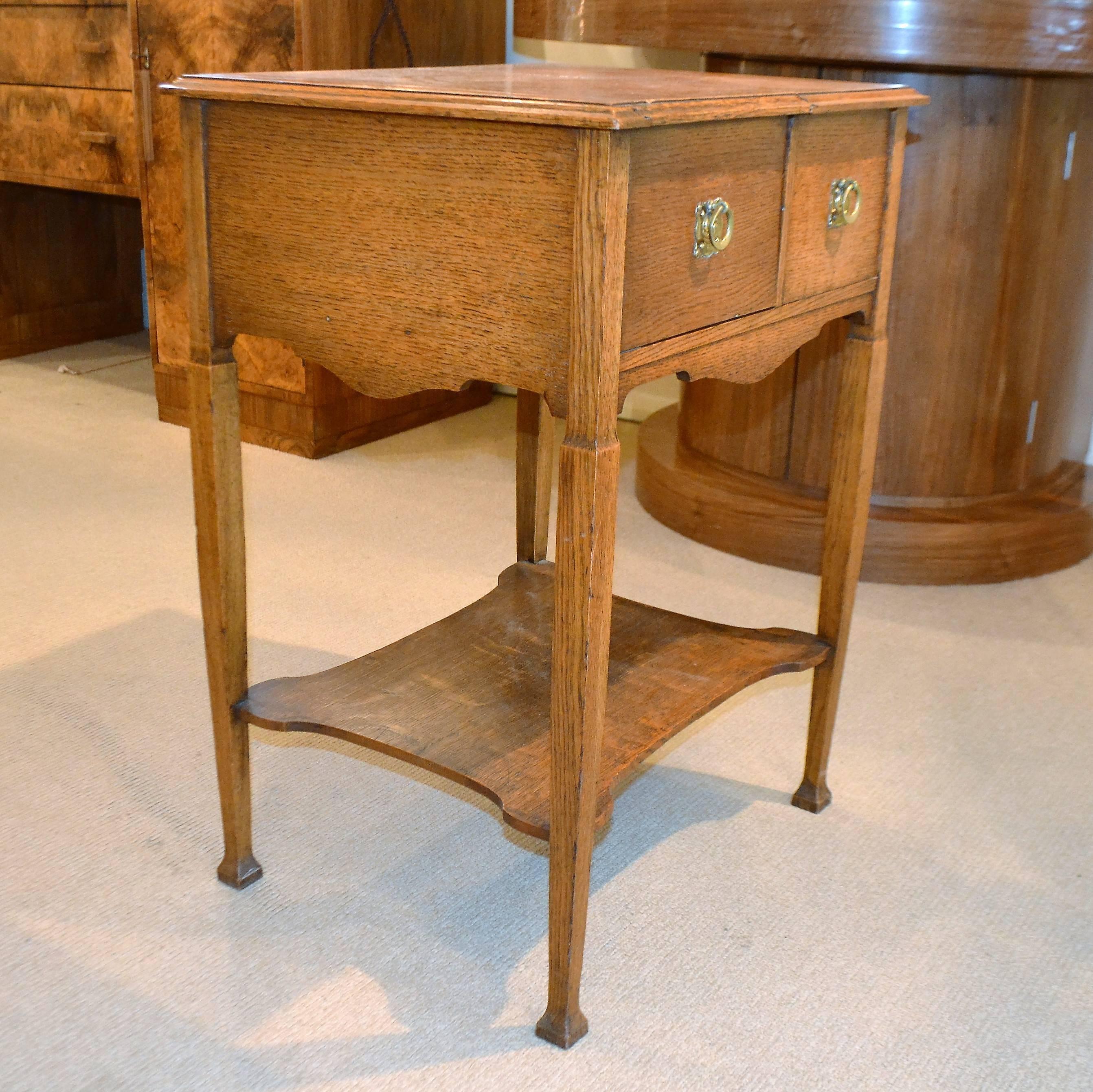 An ingeniously designed small oak table with brass repousse handle plates. It features a sliding top, cupboard and drawer, with fitments for the enjoyment of tobacco. A real conversation starter, and with many potential uses today. A good example of