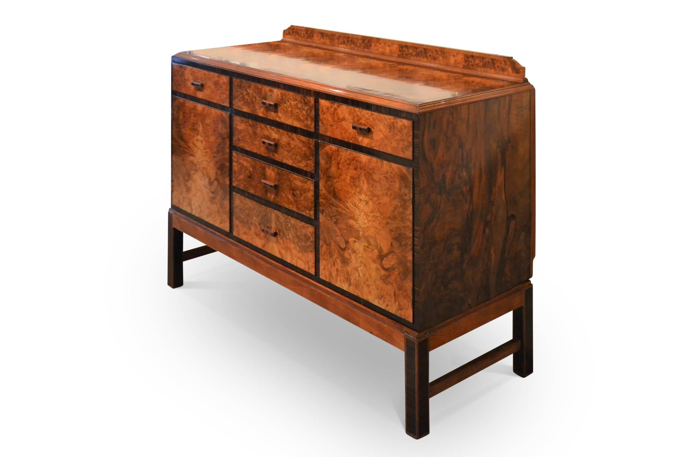 This sideboard in the Art Deco or Modernist style is a fine quality piece of hand-craftsmanship in burr walnut veneers with banding in Macassar ebony. Hand-cut dovetail joints to drawers. Bears label to back: 'A H Holden, Hammersmith School of Arts