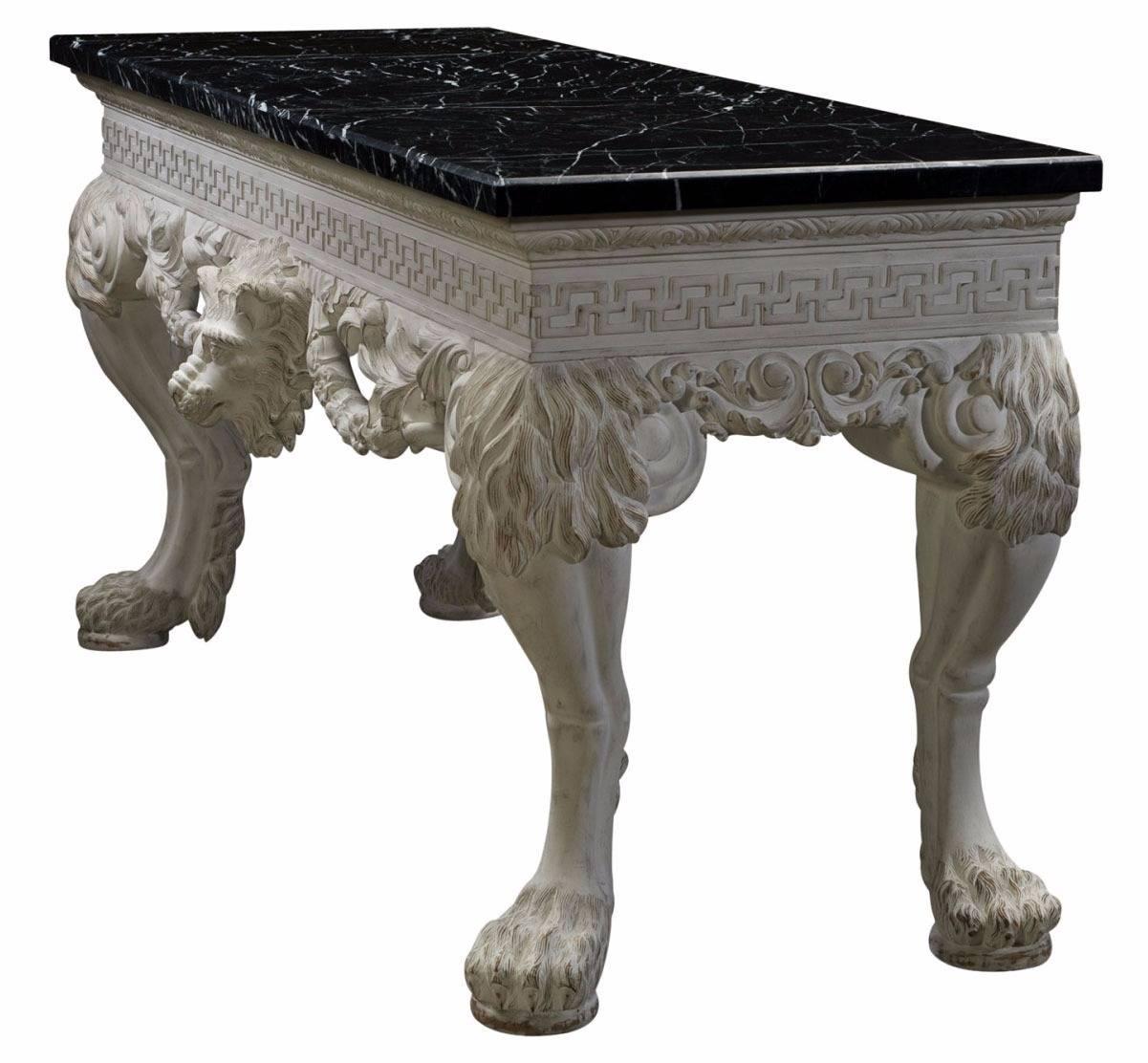 A magnificent and finely carved and white painted console table, the veined black marble top above a Greek key carved frieze with a central lion head and leafy swags below, the bold naturalistic hairy lion legs with paw and disc feet. The original