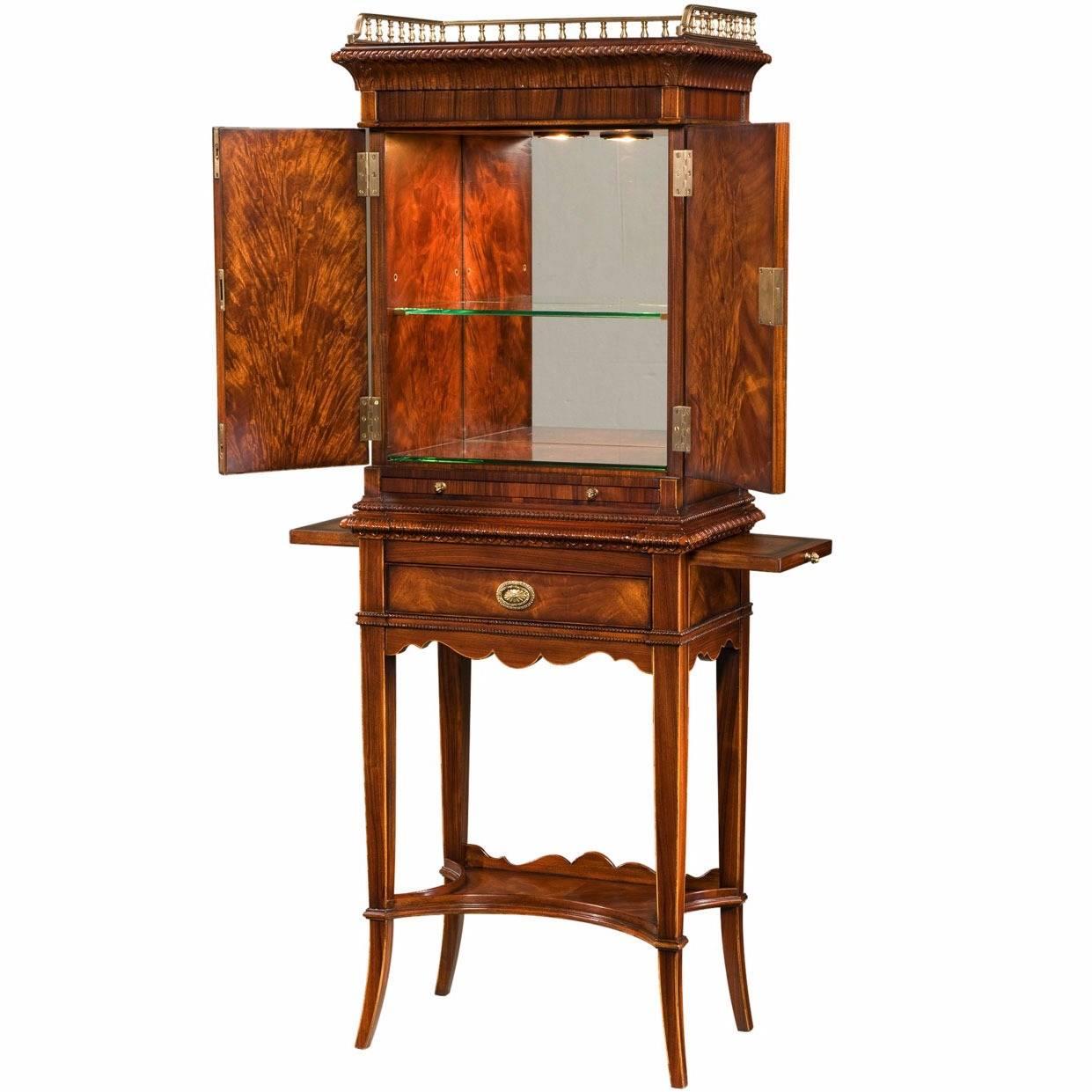 A George III style mahogany and rosewood cocktail cabinet with panelled doors and slides below. The stand has a drawer, undertier and splayed legs. The interior has mirrored back, glass shelves and 3 stage touch light. The original 1800.