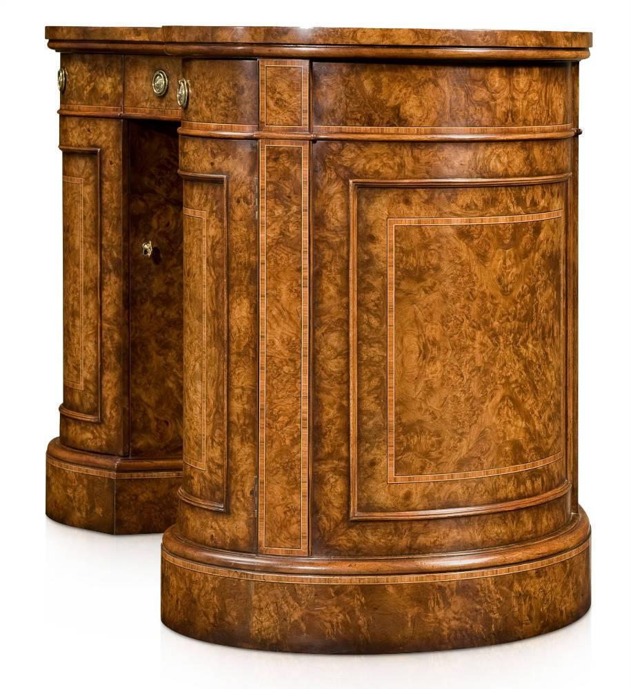 A walnut burl veneered, crossbanded and line strung kidney shaped pedestal desk, the burnished leather inlaid and hand tooled top above three frieze drawers, the burl veneered kneehole, flanked by a cabinet door to each pedestal enclosing four