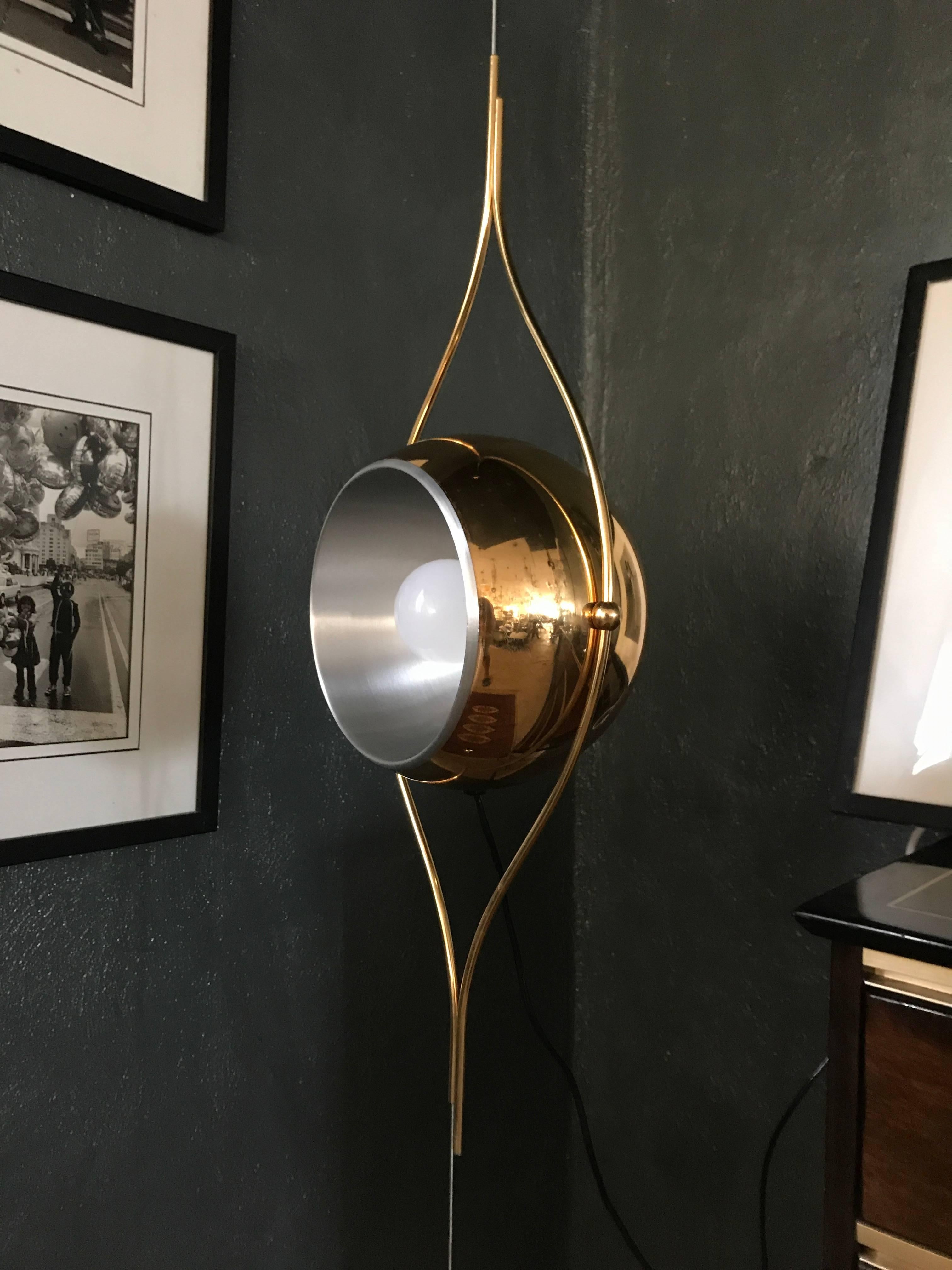 Beautiful and extremely rare pair of golden chandeliers / pendant lights by Lamter Milano,
The lamp resembling a vertical eye, is suspended on a steel cable and can be adjusted as low or as high as desired by simply sliding it on the cable, which is