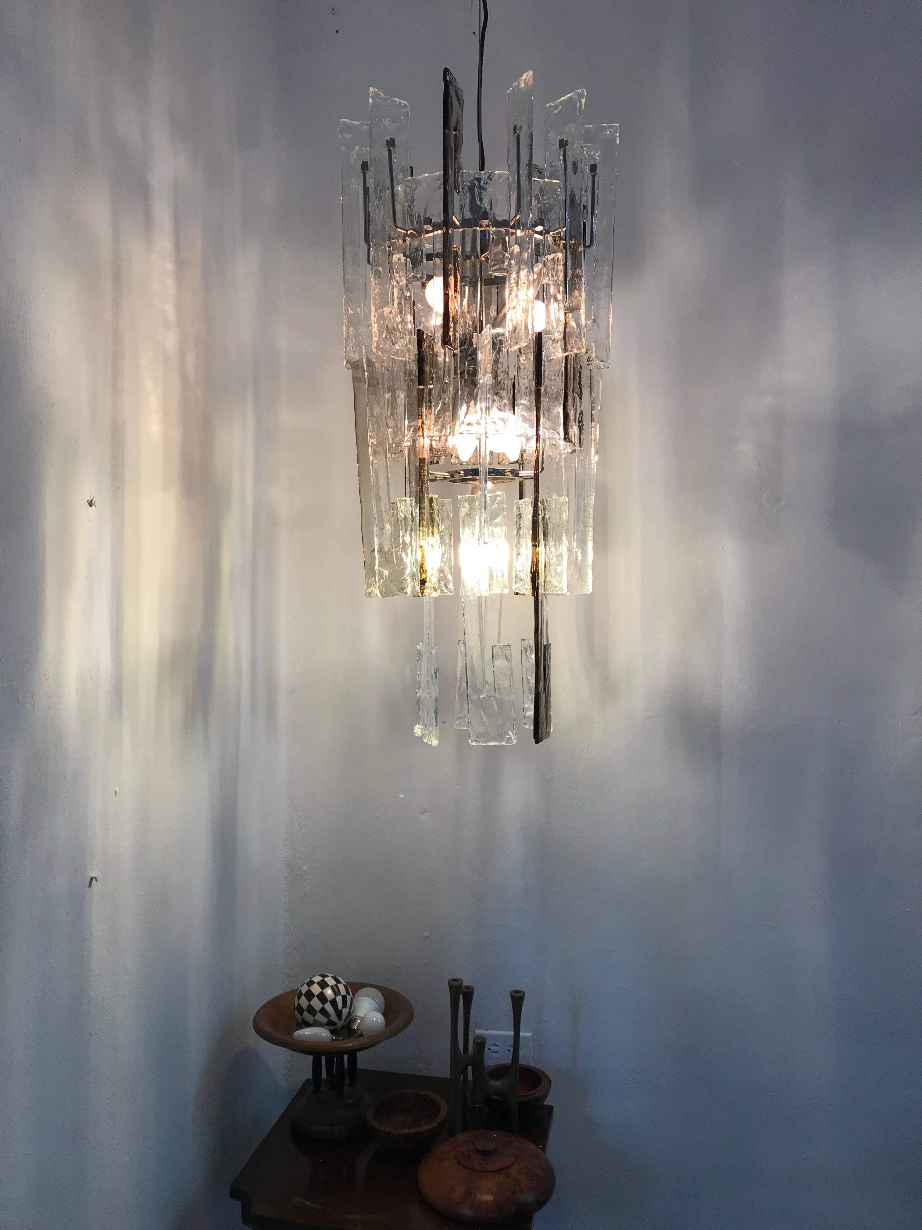 Beautiful Mid-Century Modern chandelier consisting of interlocking C shaped glass links in clear and smoked Murano glass and a Metal structure with 9 lights.
Designed by Carlo Nason and produced by Mazzega, circa 1960.