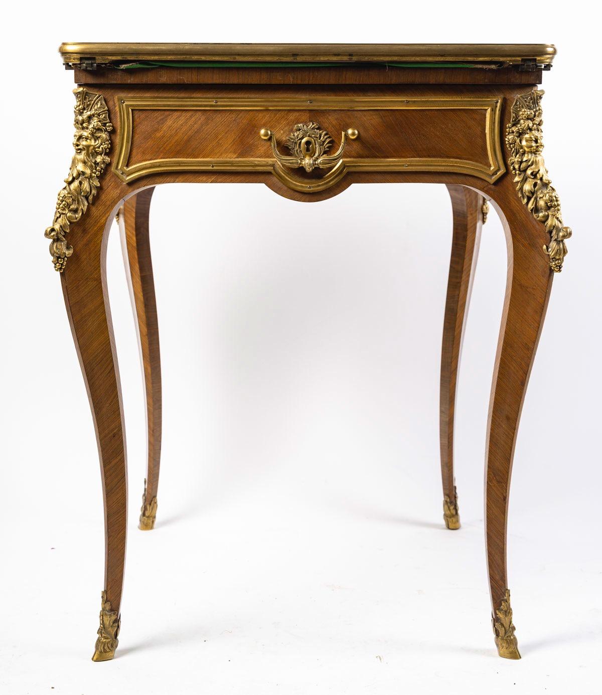Un raffinato tavolo da gioco francese per buste in legno di re, ornato di ormolu, di Sormani Paris. 
Il piano girevole a ribalta racchiude un interno foderato in baize dorato con utensili, sopra un cassetto a fregio;
Il rovescio è caratterizzato da