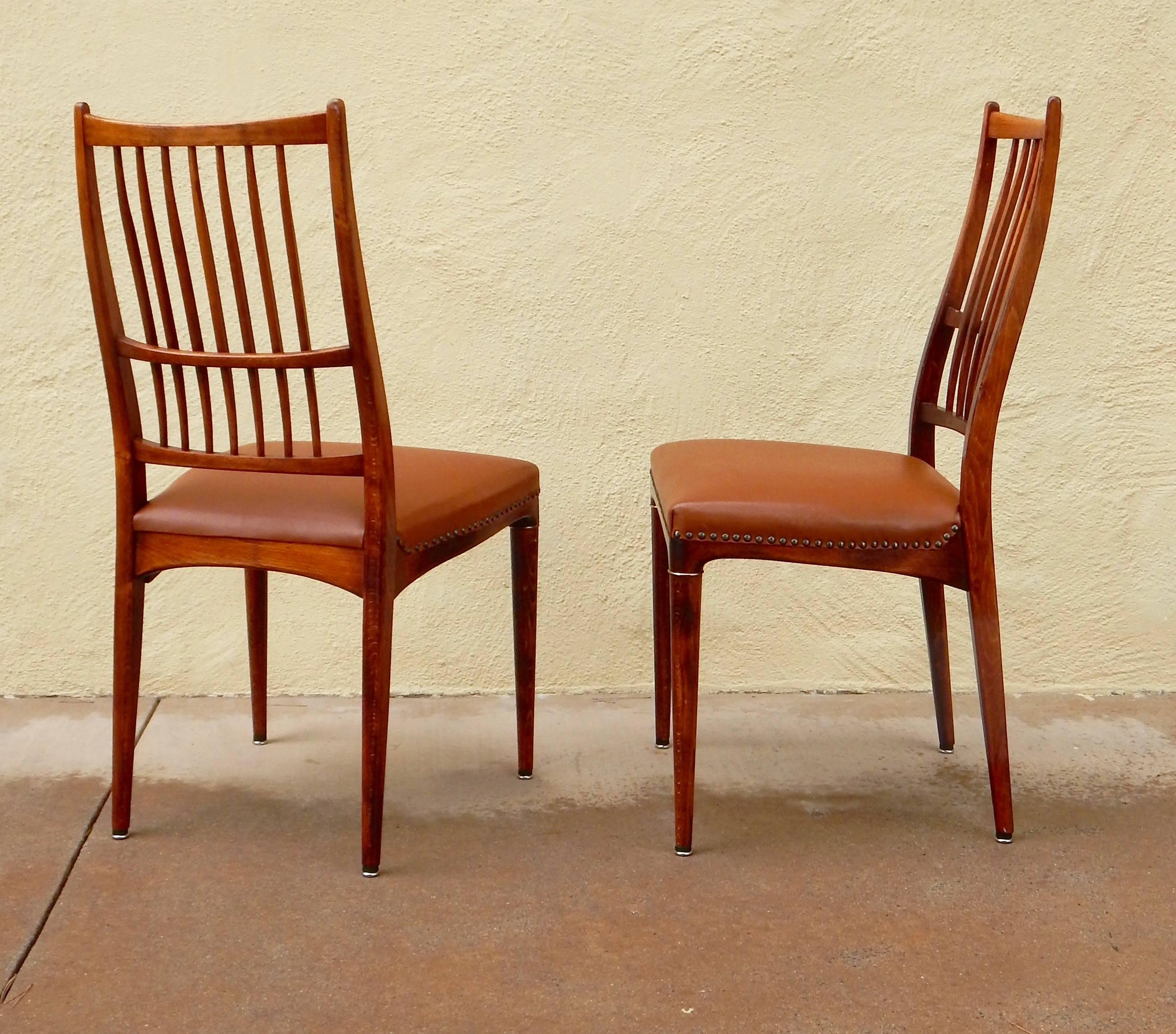 Set of four Mid-Century Modern dining chairs in stained birch wood. Sinuous, sculptural form. Leather seat with nailhead detail. Extremely pleasant to sit in and in excellent original condition. I have an additional four of these if needed for a set