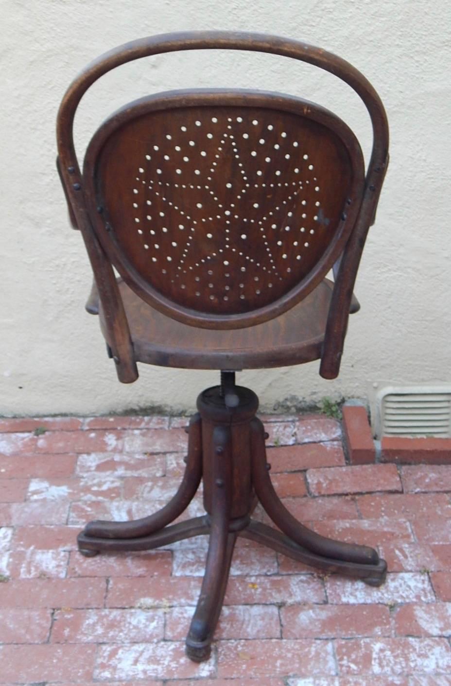 Arts & Crafts era swivel chair crafted in oak. With hole punch detail at seat back. Height adjusts as you turn. In excellent original vintage condition, with some cracking-see detailed photos. Made by Josef Kohn Company in Vienna, Austria, circa