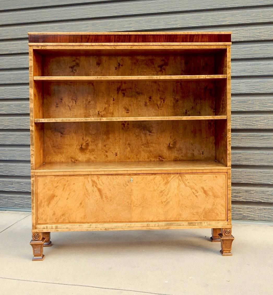 Swedish Art Deco bookcase or cabinet. The case is composed of highly figured golden flame birch wood with rosewood banding. The original shelves are adjustable and removable. There is a locking cabinet with drop down door at the bottom of the piece