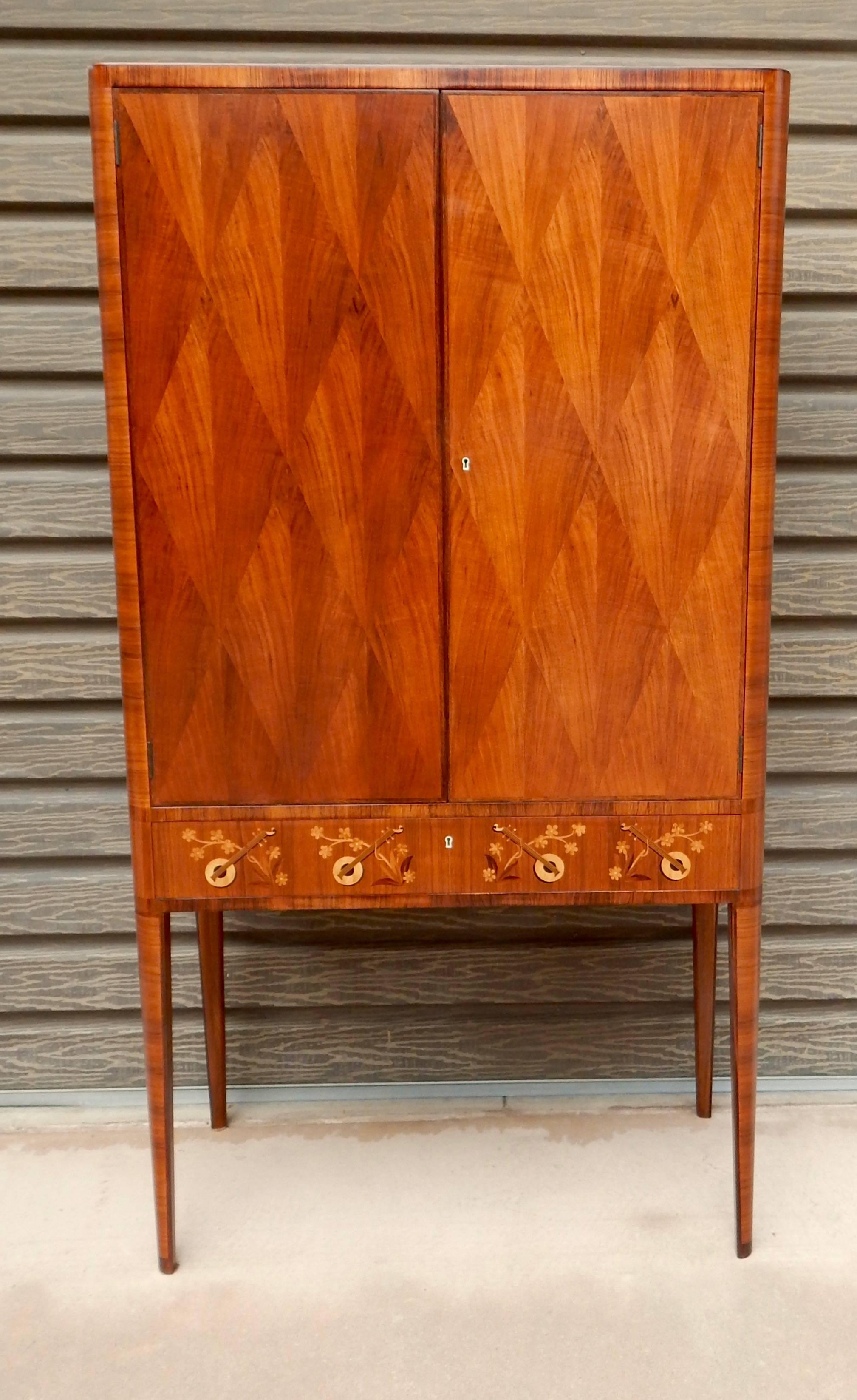 Swedish inlaid storage cabinet, circa 1940. Doors in diamond pattern bookmatched walnut parquetry. Drawer with marquetry in musical instrument theme. This cabinet was just restored to its original luster by our craftsmen.