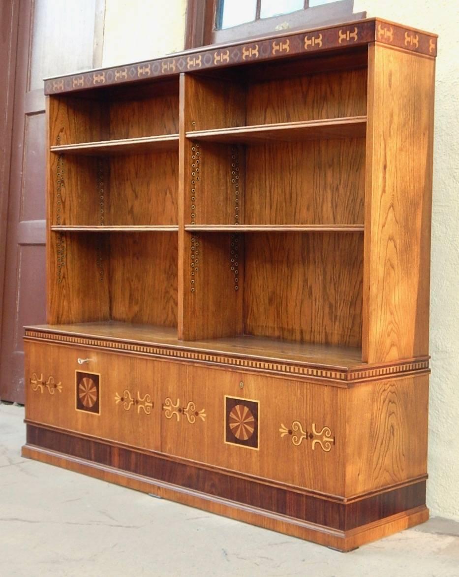 Late arts and crafts inlaid bookcase rendered in elm and inlaid in birch and rosewood. Four original shelves also in elm. Shelves are adjustable. Two cabinets at base with locks. Beautifully restored by our craftsmen, Sweden, circa 1920.