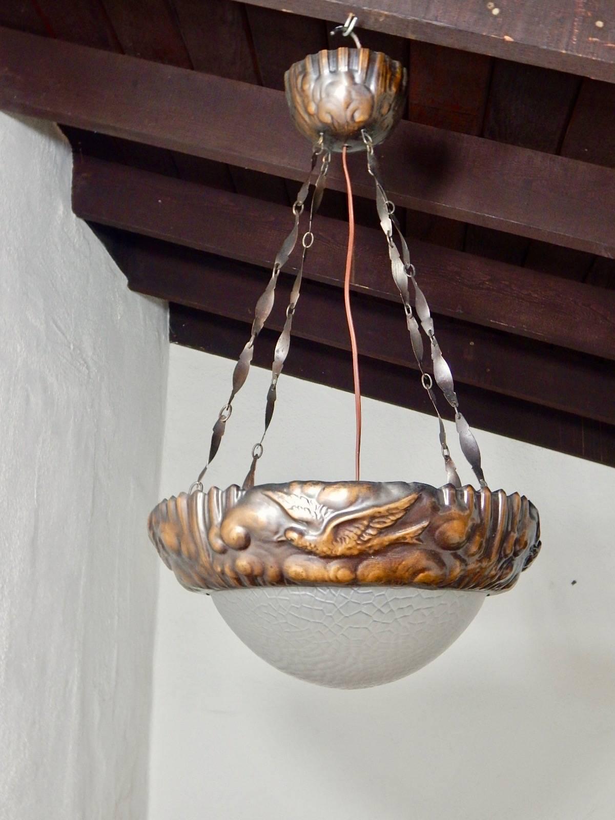 Swedish Arts & Crafts era hanging light fixture rendered in hand-hammered copper. 
With hammered motifs of fires and clouds. Glass bowl is original. There is one electrical socket which illuminates the center of the bowl. Price included complete