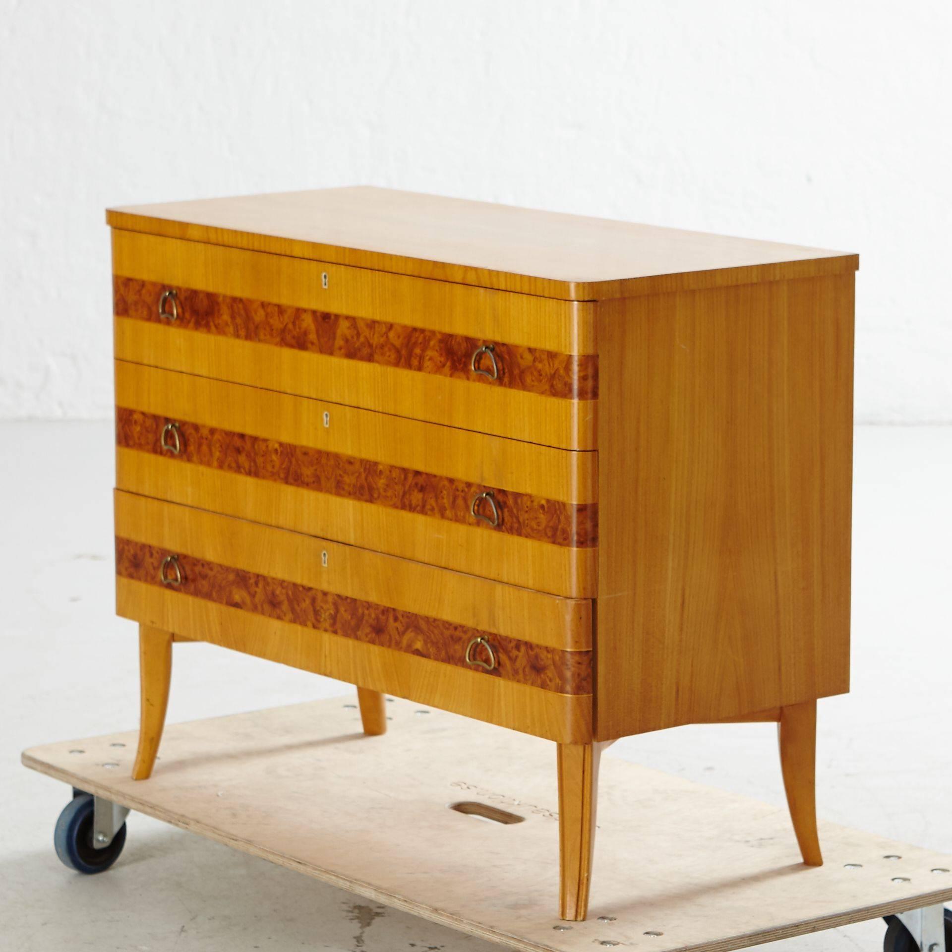 Swedish art moderne three-drawer dresser in elm and carpathian elm. Designed by Axel Larsson. Original metal pulls. Four saber legs. Original key. Restored and in pristine condition. Made at Bodafors in Southern Sweden in the 1940s. Contact us for