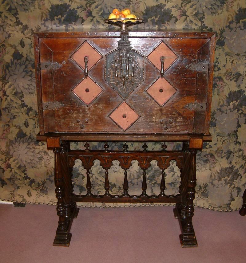 A fine Spanish walnut vargueno dating from circa 17th century to 18th century, the stand circa 19th century. The rectangular chest having decorative pierced brass mounts backed in red velvet with an engraved iron hasp, lock-plate, original lock and