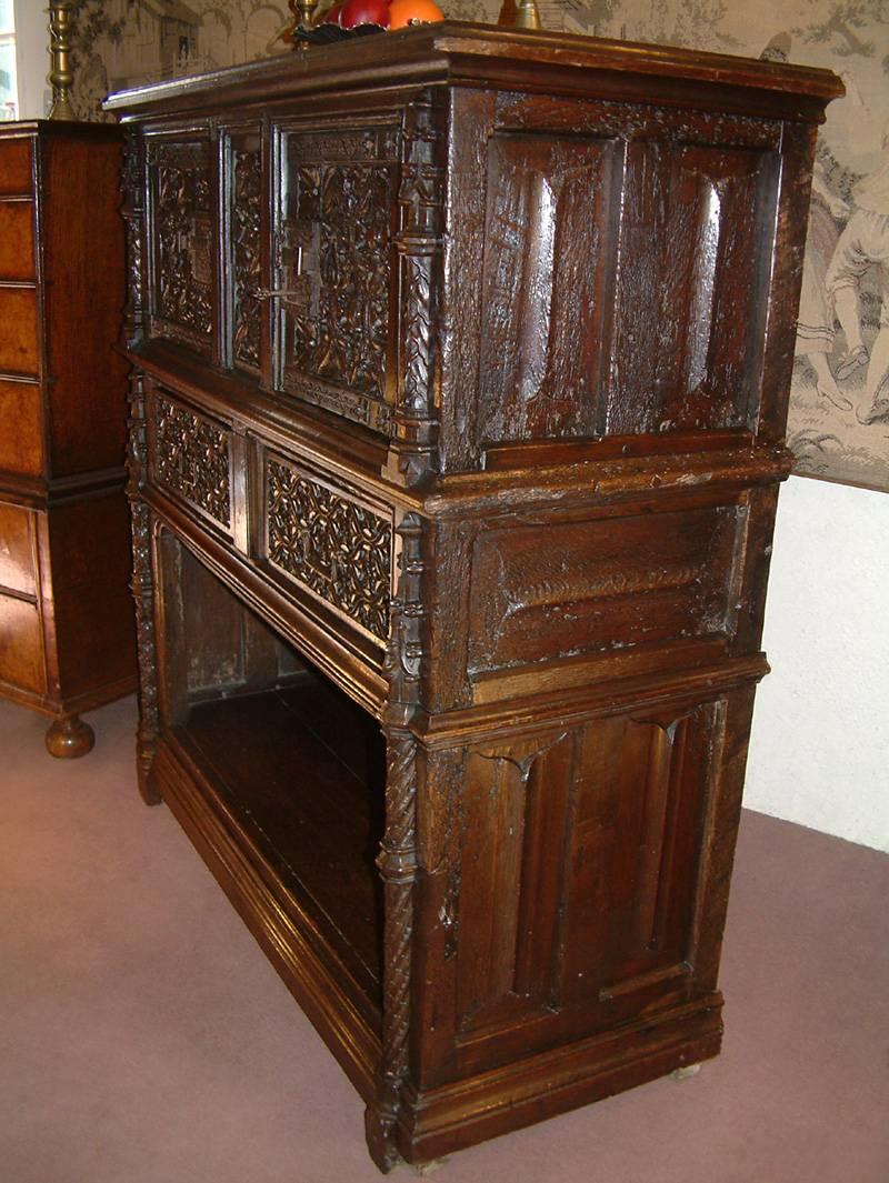 An extremely rare early 16th century oak court cupboard dating, circa 1520. The planked top with cleated ends above a central panel flanked by a pair of doors, all displaying exceptional tracery carving of floral type depicting carnations, Tulips