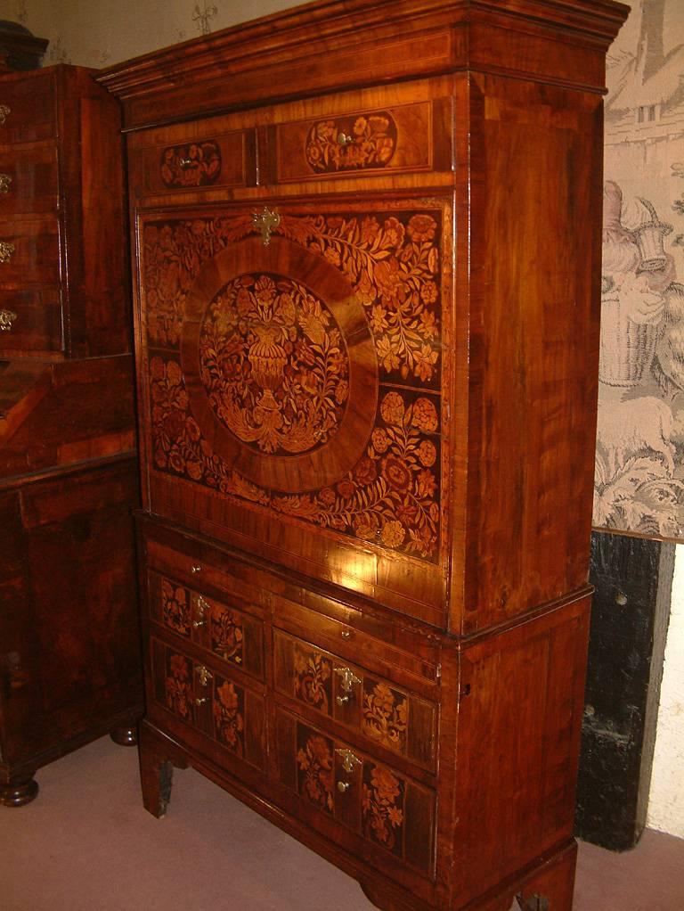 An English late 17th century walnut, floral marquetry inlaid Escritore cabinet on chest dating from circa 1690. The top with architectural moulded cornice above a pair of short drawers with Holly stringing and floral marquetry inlaid panels above a