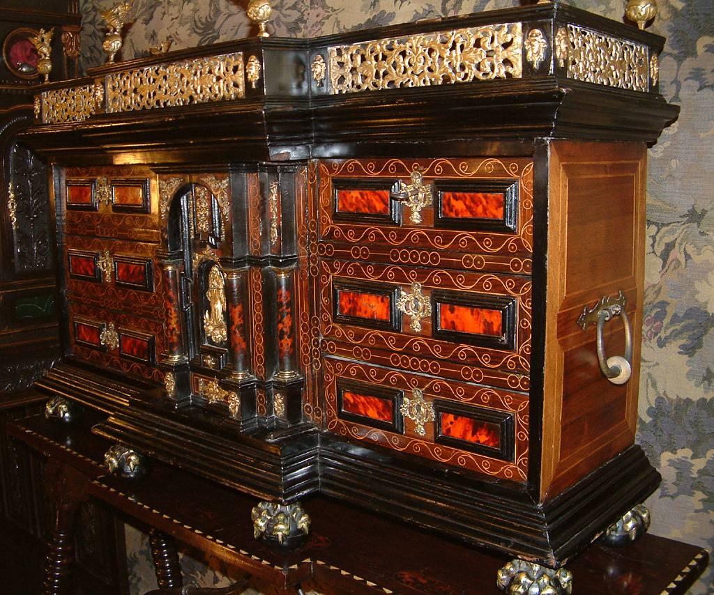 A Baroque 17th-early 18th century break fronted cabinet on stand, possibly Naples Italy, circa 1700. The galleried top with gilt brass pierced fretwork surmounted by ormolu brass eagles, above a thick moulded and ebonized frieze. Below, a stepped