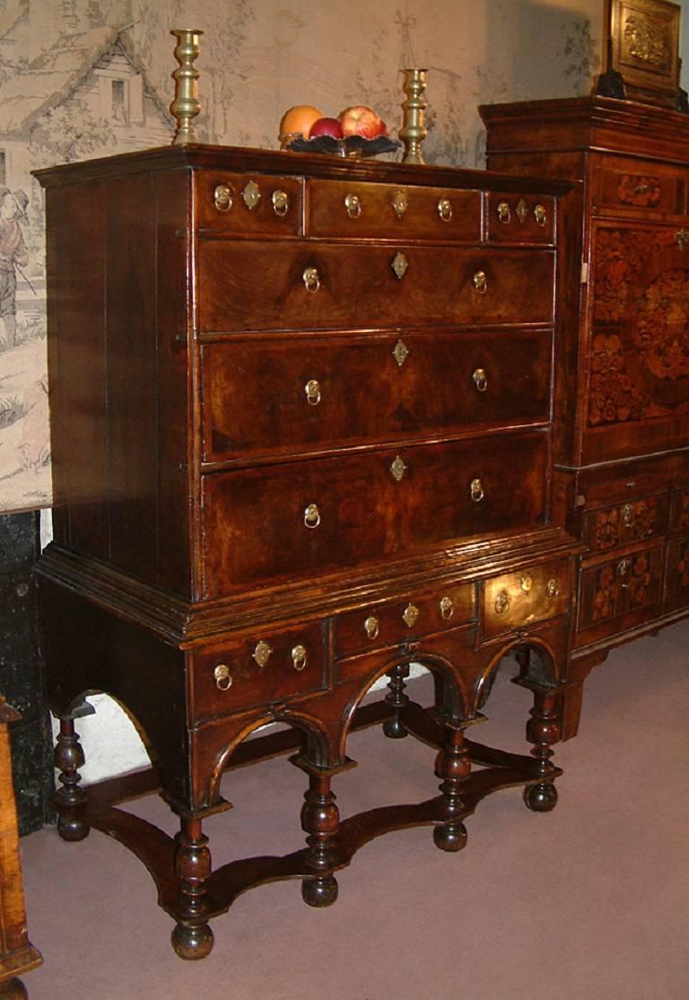 A fine 17th century William and Mary period walnut chest on stand dating from circa 1690. The top with moulded cornice above three short and three long graduated crossbanded drawers with brass handles and escutcheons and with half round split