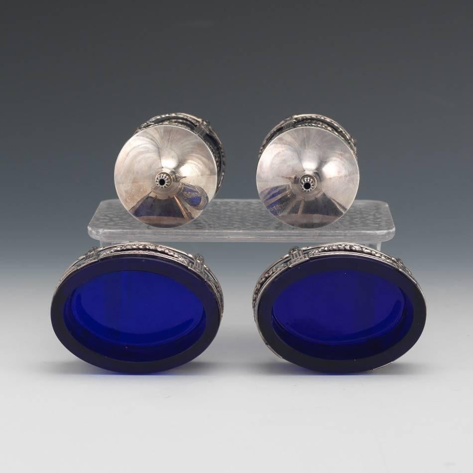 Swedish sterling silver and cobalt blue glass set of two salt/pepper shakers and two individual salts.

Consisting of: Pair of sterling and cobalt blue glass salt and pepper shakers of cylindrical shape wit silver overlay with floral garland