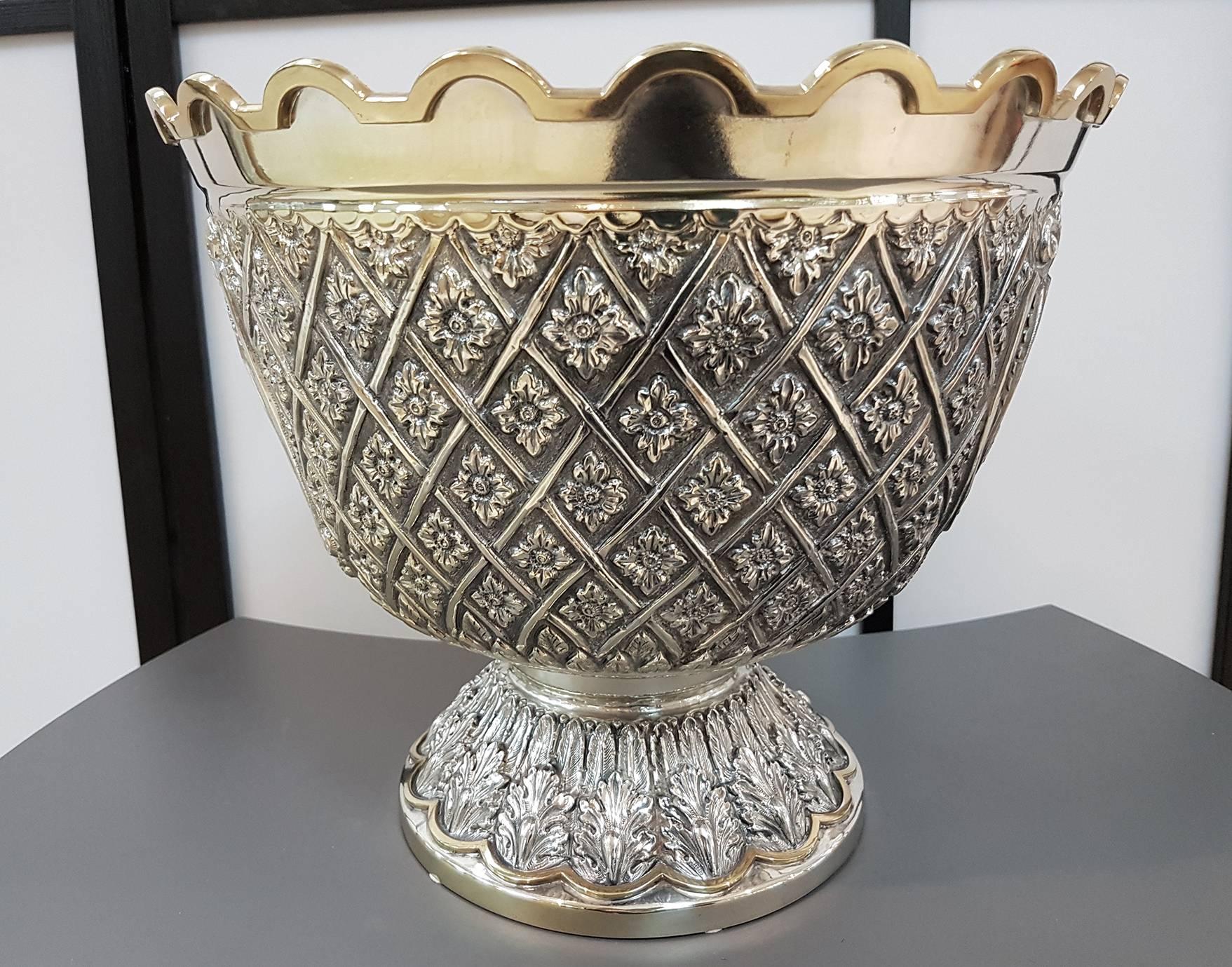 A solid silver cone shaped trunk whose rim is a scallop shaped and gilt, laid on a leaf-chiselled base.
The body is embossed and chiselled with flowers encased in a trellis and, on the two opposite sides. It is endowed with two, gold-plated