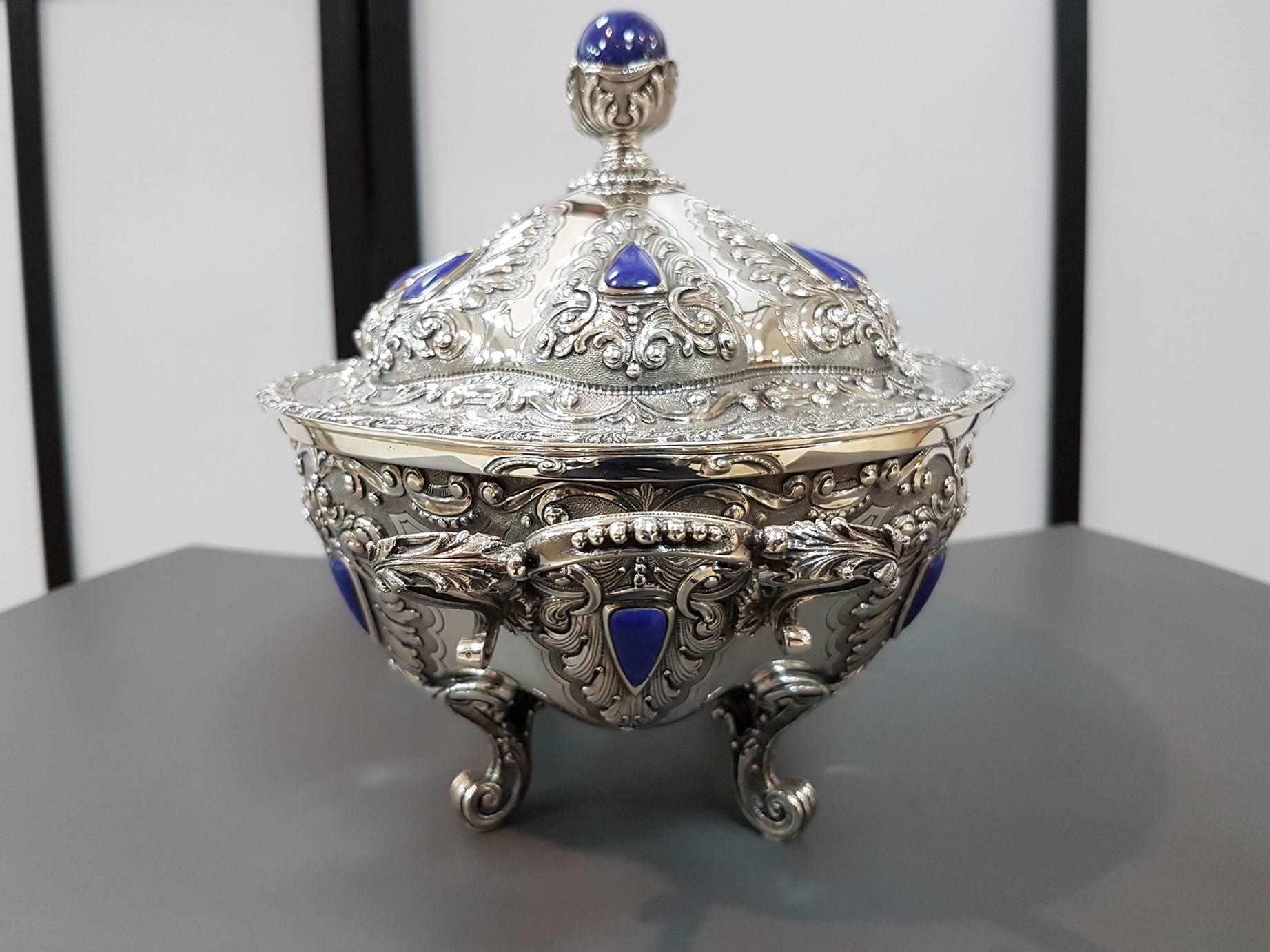 The tureen body is made from embossed, chiseled and engraved sliver sheet. The outer surface is further, artfully, embellished with lapislazuli. A great round lapislazuli encased in silver leaves acts as the lid grip.
The tureen lining is