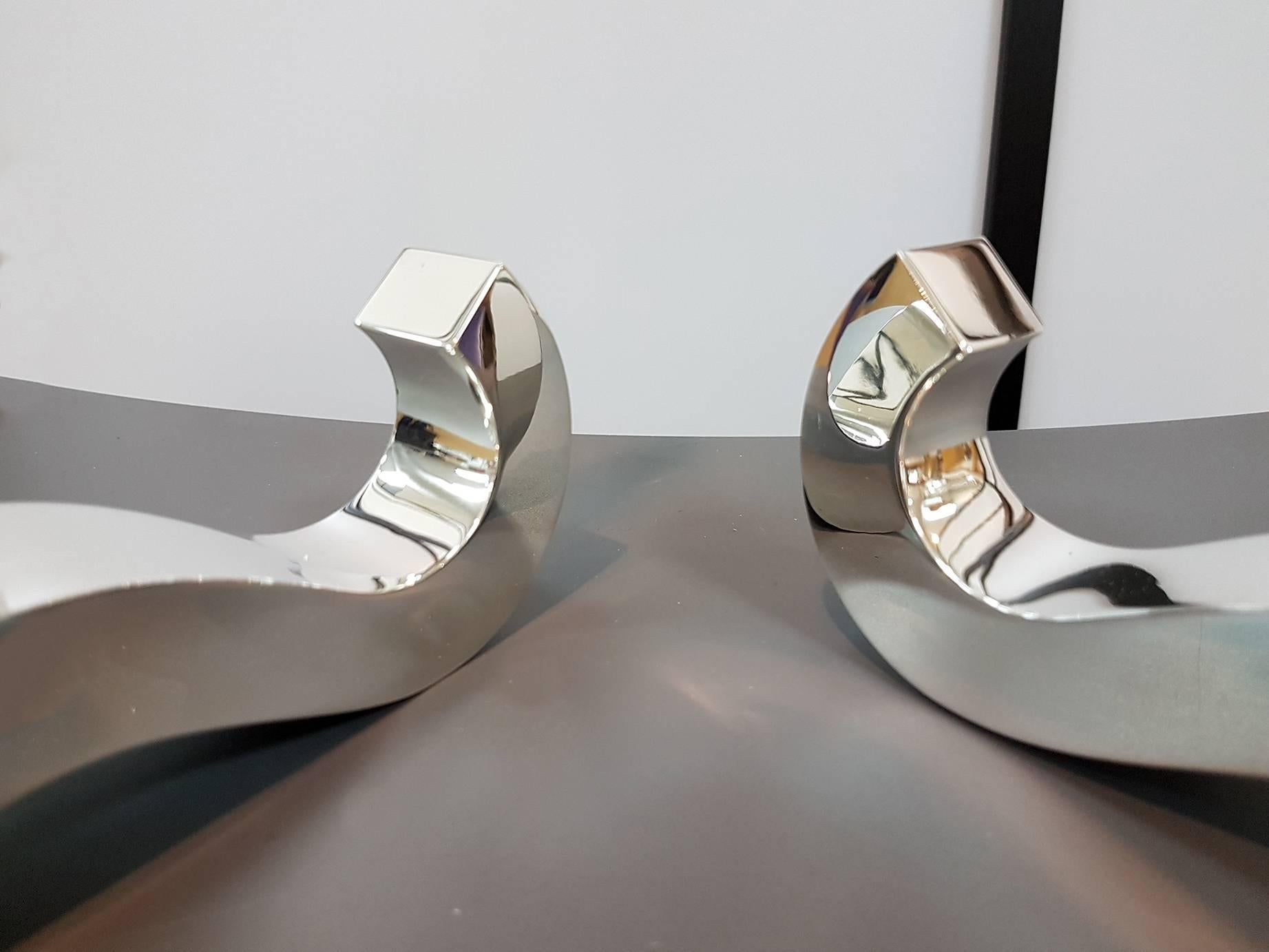 Pair of sterling silver candlisticks with one light.
The structure has been realized by a smooth sheet of silver.
The wave movement is realized with manufacturing by handmade.
On the top one rounds candle-holder are placed to complete the object
580
