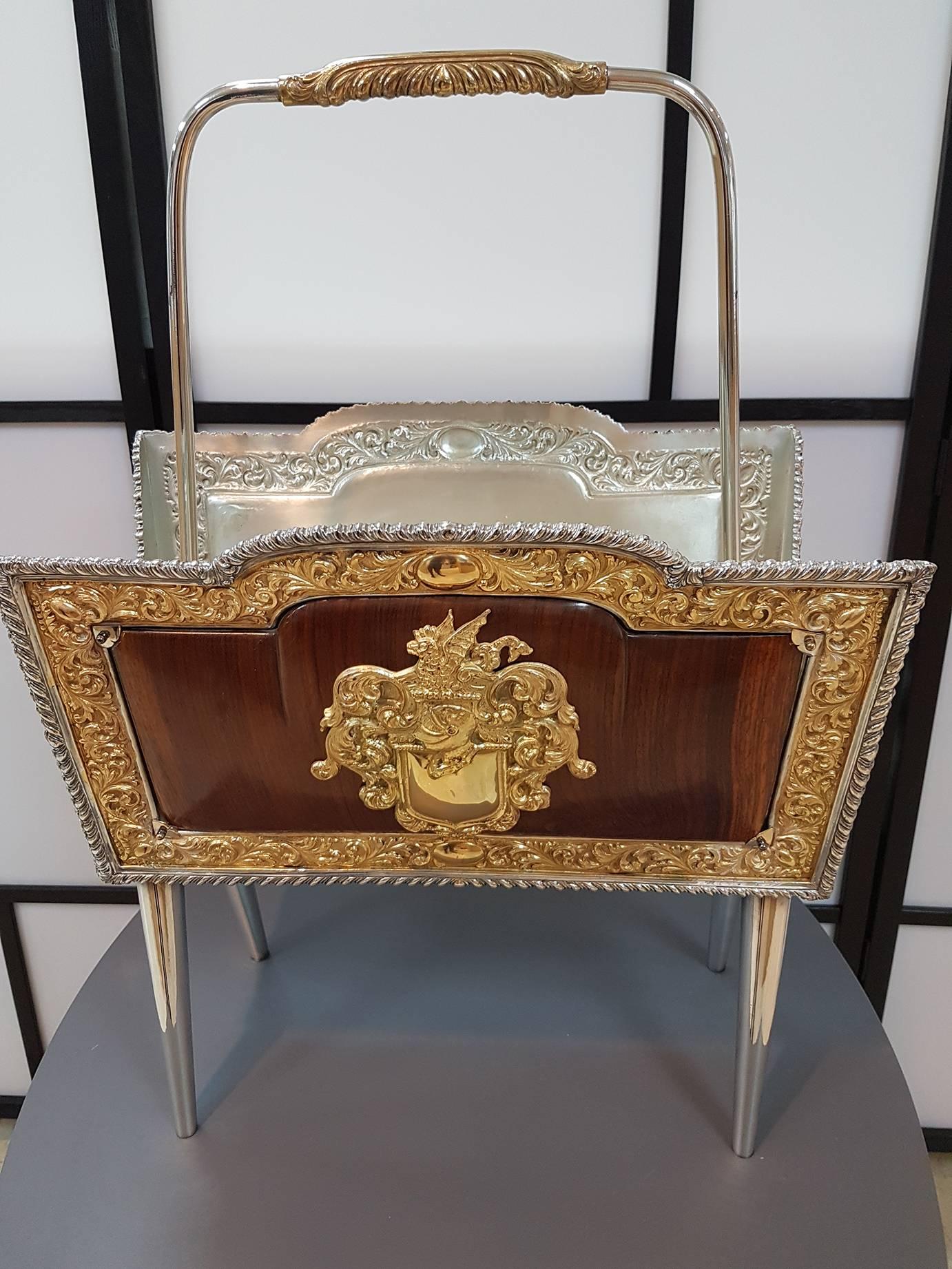 This Queen Anne style mafazine rack-frame is composed of embossed, chiseled and gold-plated silver. It has additional valuable wooden panels, at the centre of which there are two silver escutcheons on which to engrave family crests, initials or