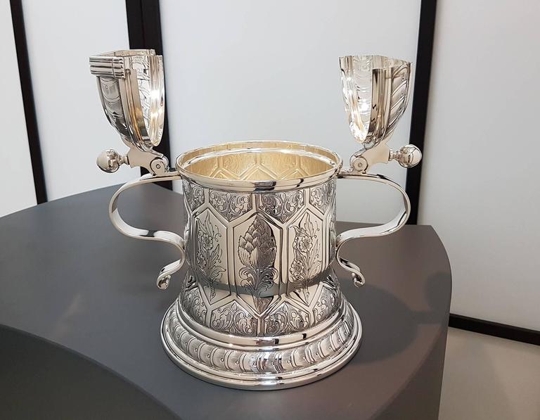 Sterling silver tankard finely hand-engraved with floral decorations framed in long hexagonal segments.
The body is cylindrical with two smooth casting handles.
The lid is double finely engraved in the same way of the base design.
1,600 grams