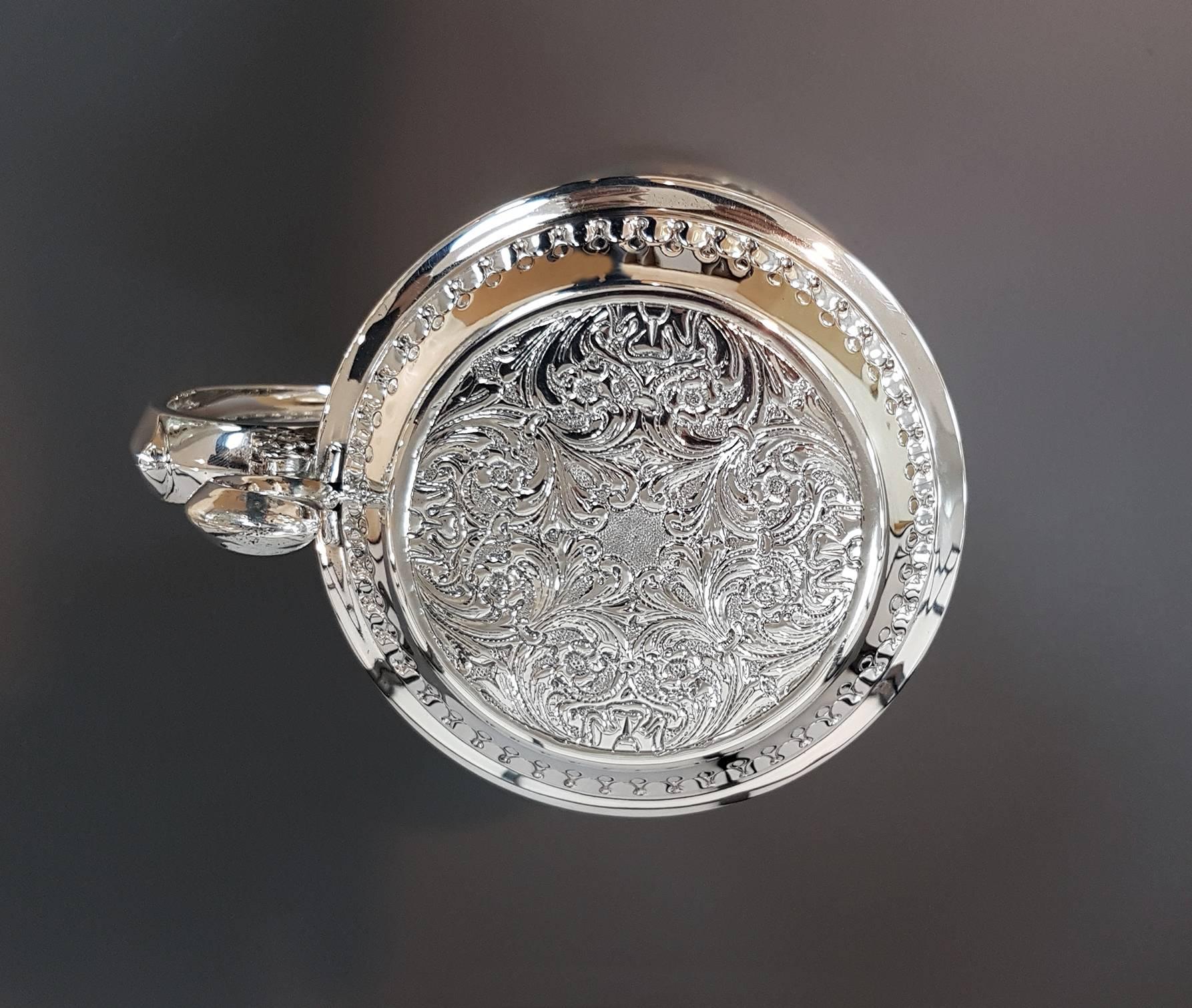 Jarra cilíndrica de plata de ley dorada por dentro.
El cuerpo está repujado y grabado a mano con volutas y flores
Medida: 730 gramos.
