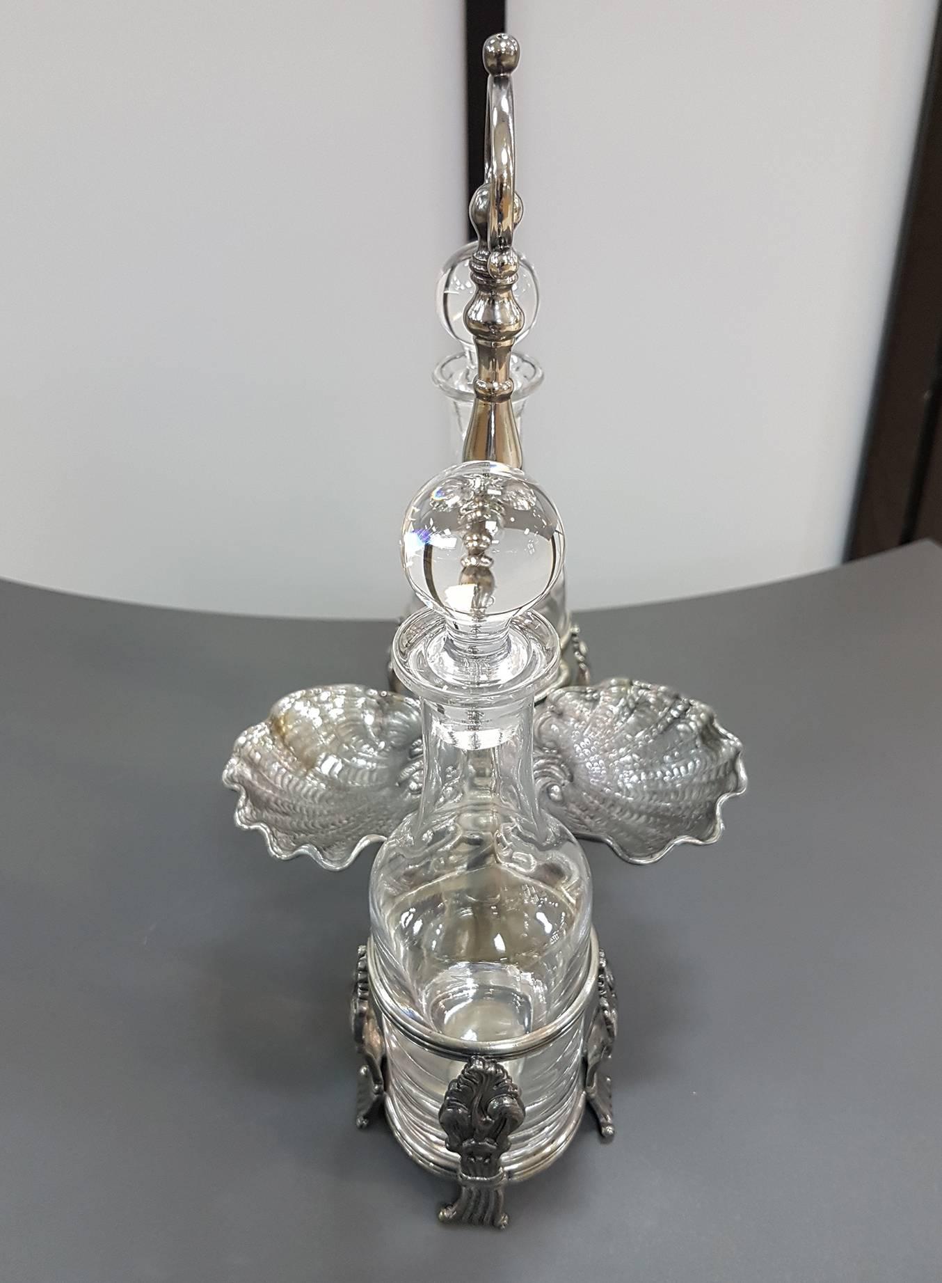 Silver 800°°/°°° Cruet - Venetian Art replica.
The original 18th century is from a private collection
The two bottle racks are made up of chiselled scrolls that also act as feet
Two large ribbed shells form the salt holder

