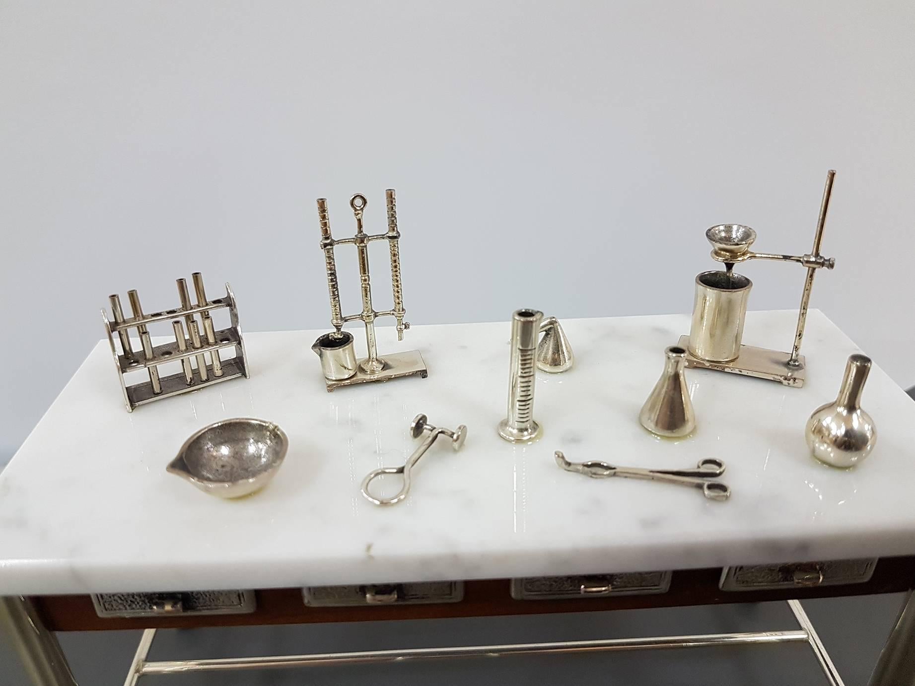 Wooden miniature with sterling silver details depicting the work table of the Chemist.
The drawers can be opened and all the details are reproduced in silver with excellent finishing.
Stool included
The tabletop is in white marble.
 