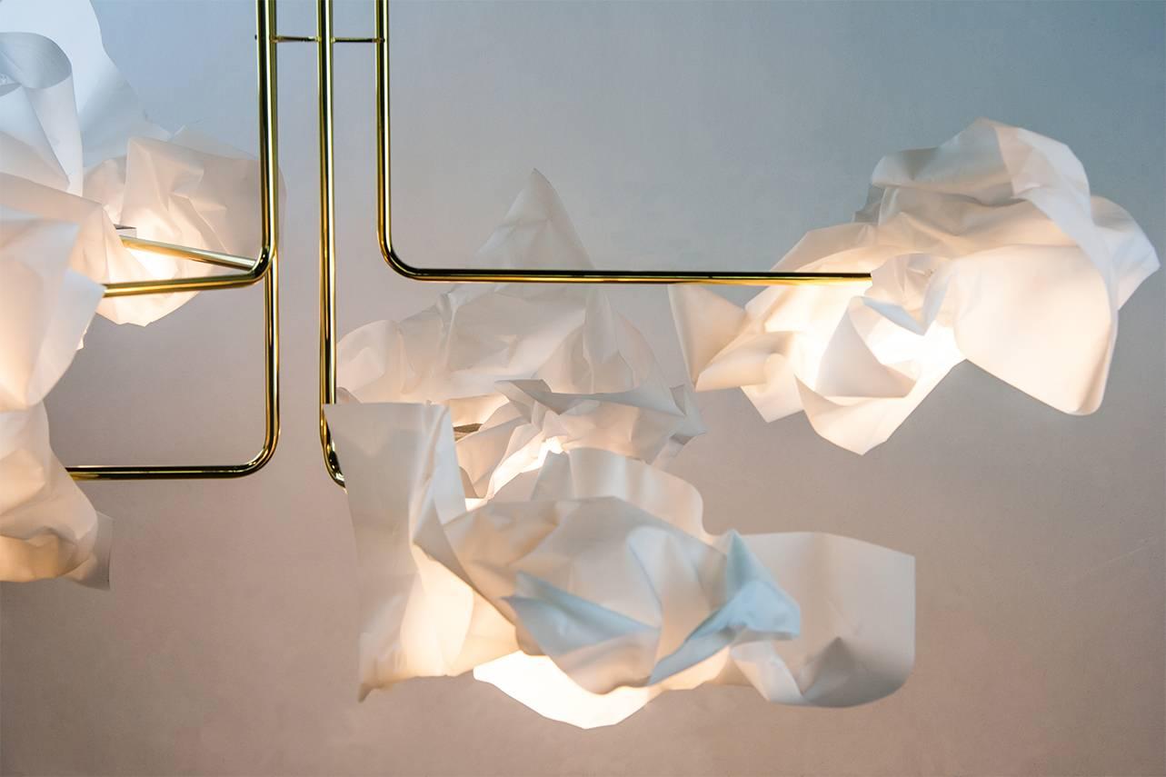 Inspired by cloud Formations whereby each is similar and yet unique in shape with subtle differences, the LED paper light shades are each individually hand-formed. Made of brass and a special plastic, the paper chandelier starts with 4 arms and can