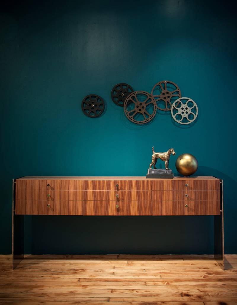 The polished stainless steel side panels appear to be pulling apart creating a tension so strong that is seems suspends the body of the walnut credenza. This piece is perfect for a living room, dining, or office with it’s strong presence.

Please
