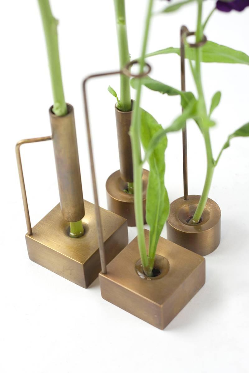 Each of these delicately, handcrafted bud vases is perfect as an individual home accessory or whimsical series. Made of brass and hand tarnished, each bad vase has its own unique formal language made from the base and stem support. In addition to