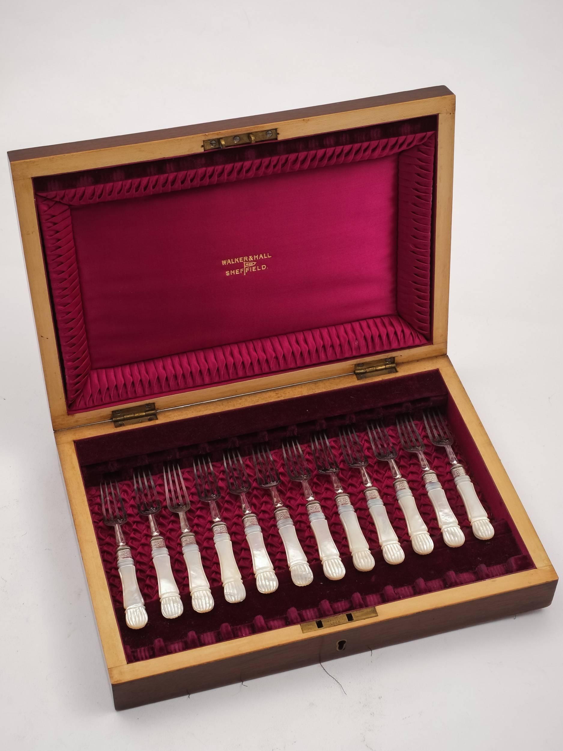 A stunning cased English Edwardian 24 piece dessert set which consists of 12 forks and 12 knives, all of which are silver bladed, beautifully engraved and have carved mother-of-pearl handles. Presented in original red silk and velvet lined mahogany