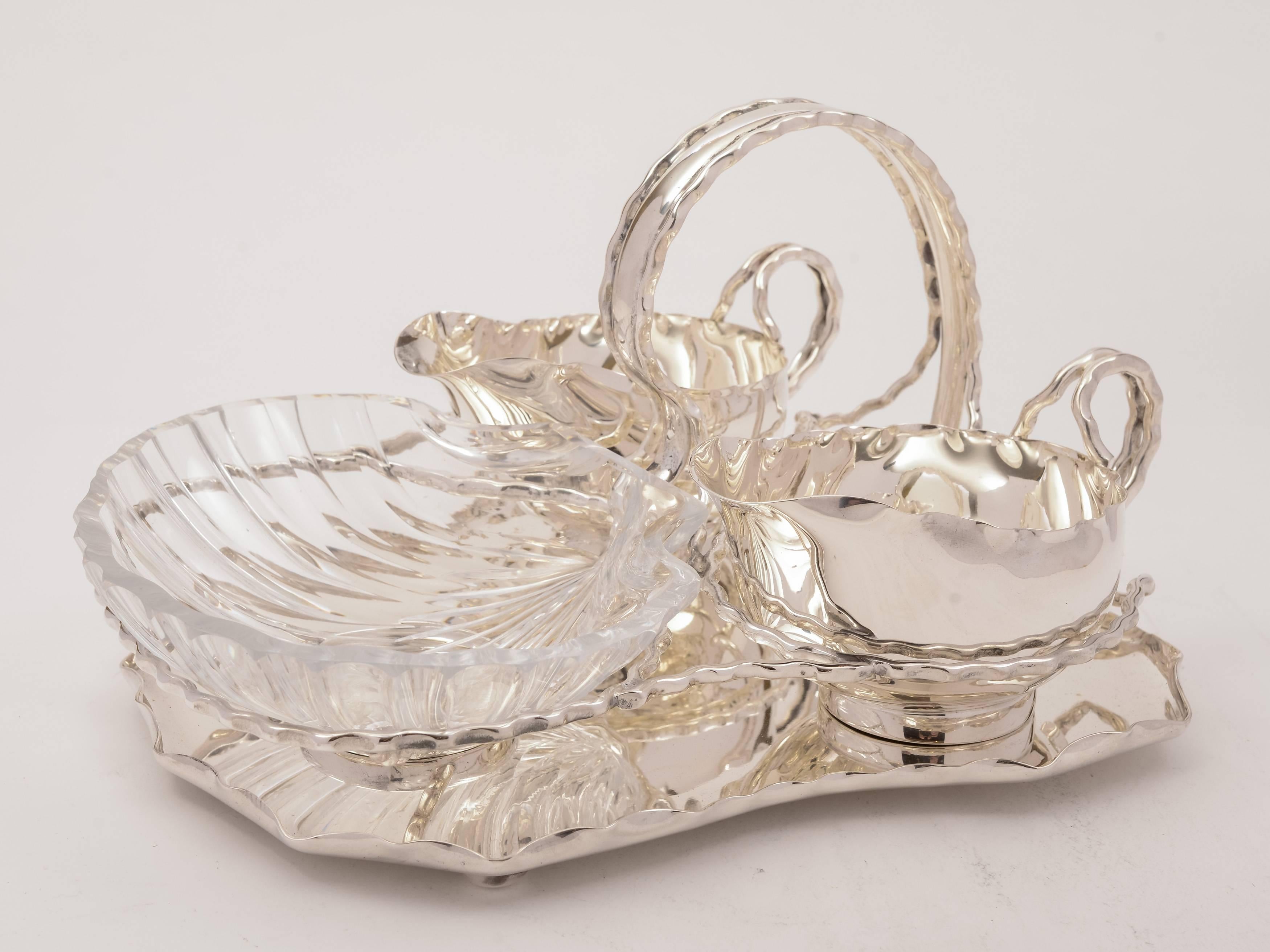 A very unusual English Victorian seafood serving set comprising of X2 silver plated sauce boats and a cut-glass, scallop shaped dish all of which sit in a silver plated serving caddy with handle, circa 1890 and marked 'H & H' for the renowned maker