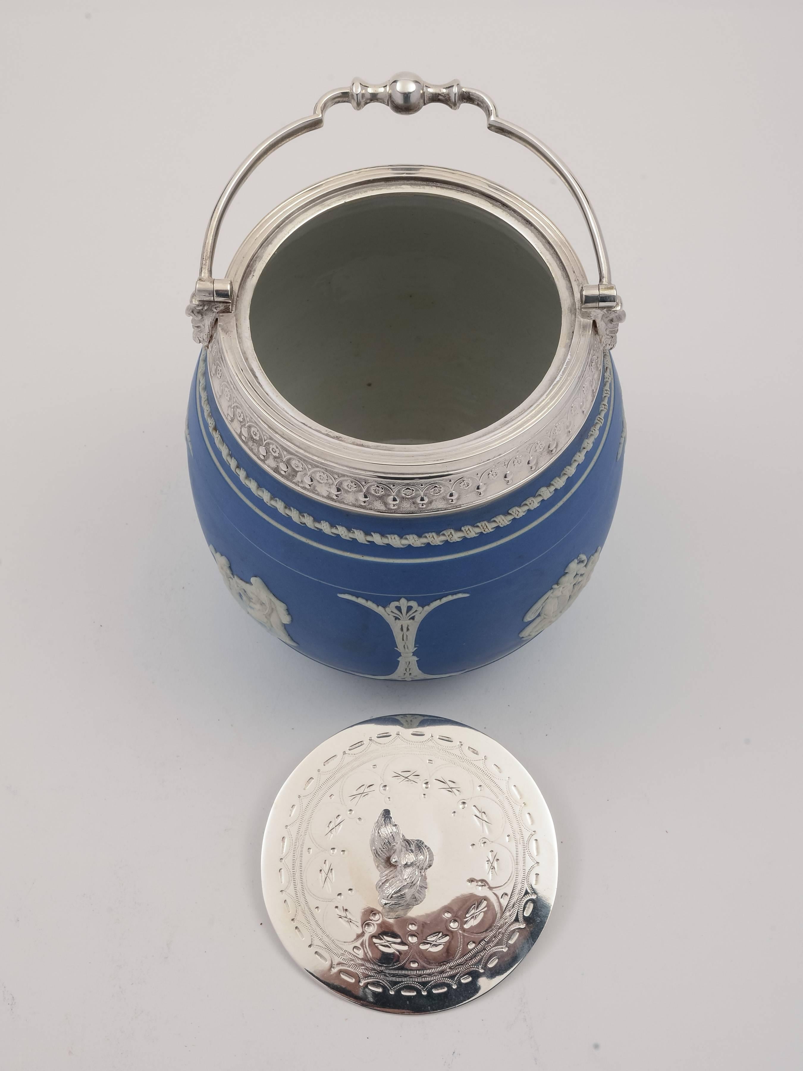 A lovely English Victorian blue jasperware china biscuit barrel with folding loop handle and embossed silver plated lid. The china body has four classical scenes in relief and is unmarked but possibly made by Wedgwood, circa 1890.

Would make a