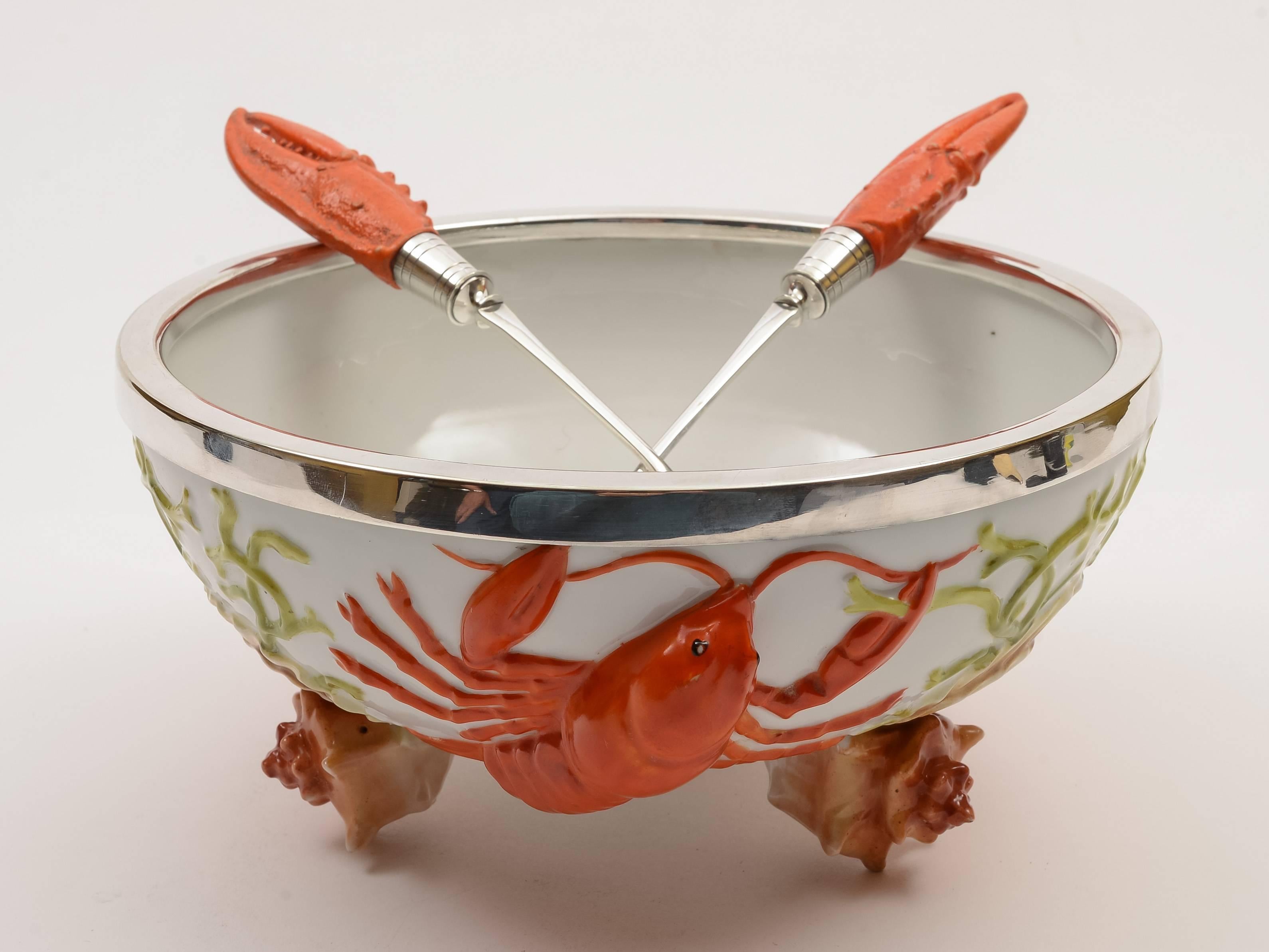 A superb Edwardian continental china salad bow with lobsters crawling up the outside of bowl which has silver plated protective rim. Also sits on shell feet with matching silver plated and china lobster claw handled servers, circa 1900.

Length of