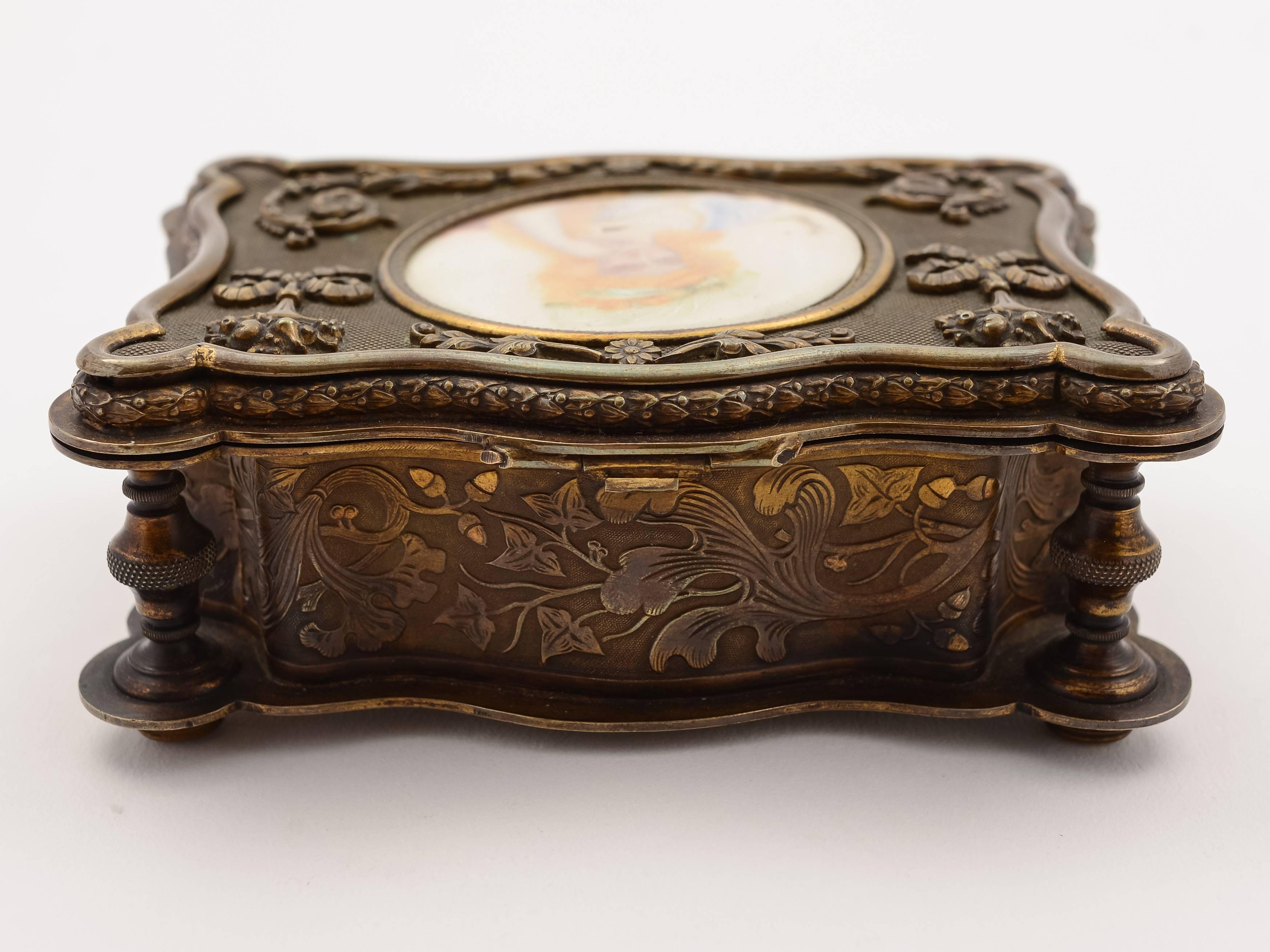 A pretty French brass jewelry casket with embossed decoration and central round painting of lady in early 19th century costume under glass. The picture is signed 'Devval' and the box has original blue velvet lining, circa 1880.

Measure: Total