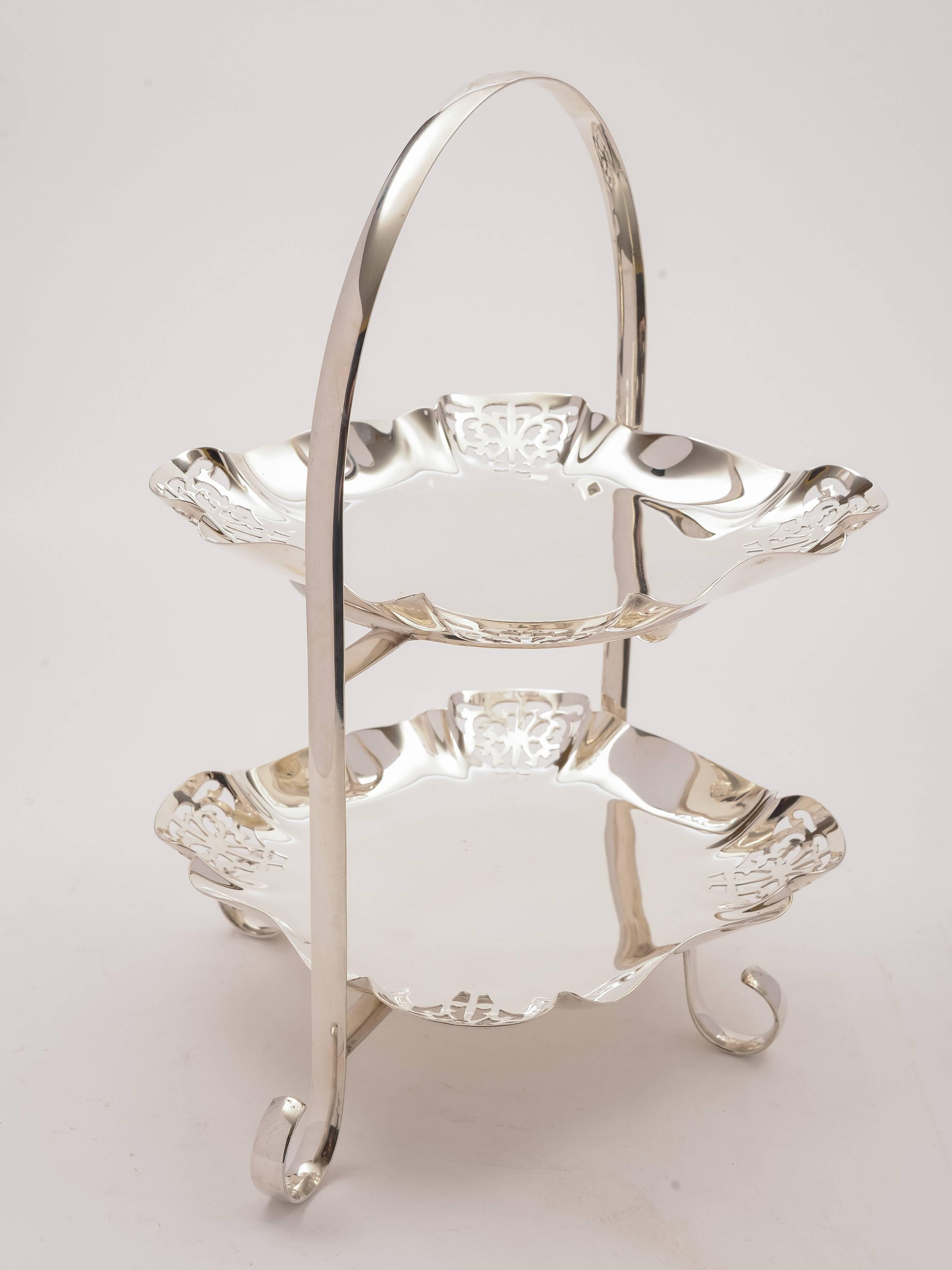 A nice English silver plated two-tier cake stand with square shaped dishes which have pierced decoration to the corners and stand on ball feet. The plates are detachable, circa 1920.

Measurements:
Height: 12