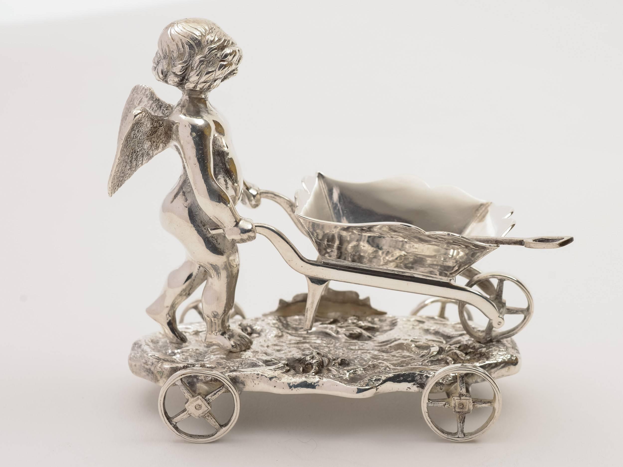 A sweet English Victorian silver plated table salt of cherub pushing a wheelbarrow. Has salt spade and sits on base with functioning wheels and shield that has the words 'Anything in my way' engraved, circa 1880.

Worldwide, first class, tracked